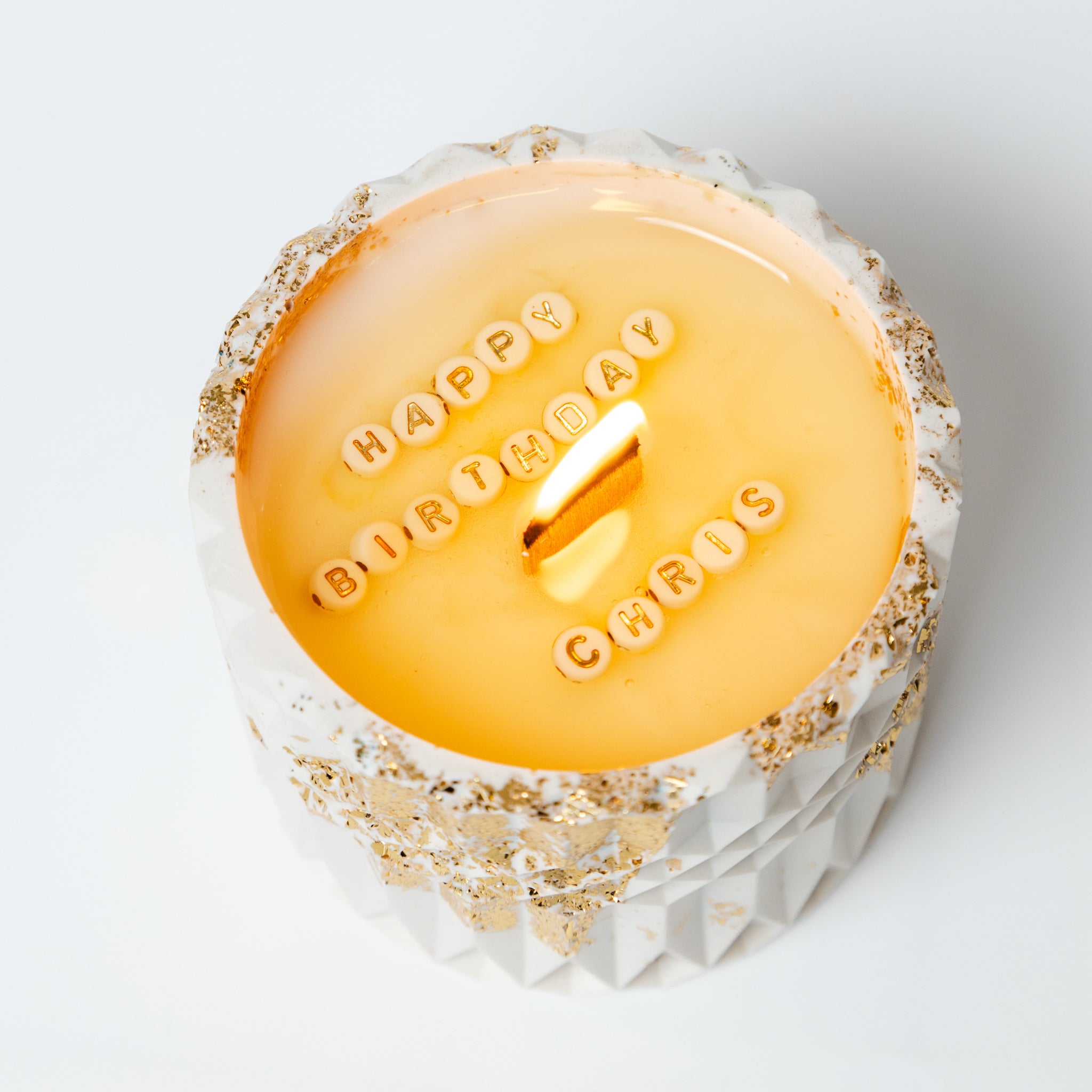 Close-up of a custom secret message candle as the natural soy wax melts to reveal hidden lettered beads.