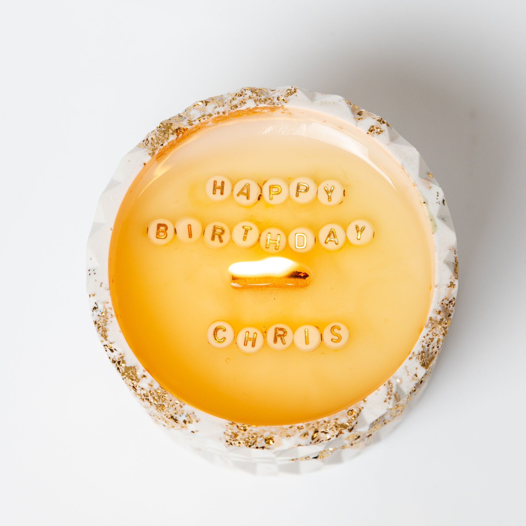 Top view of a personalised soy wax candle revealing the hidden message 'Happy Birthday' in a white Jesmonite pot.