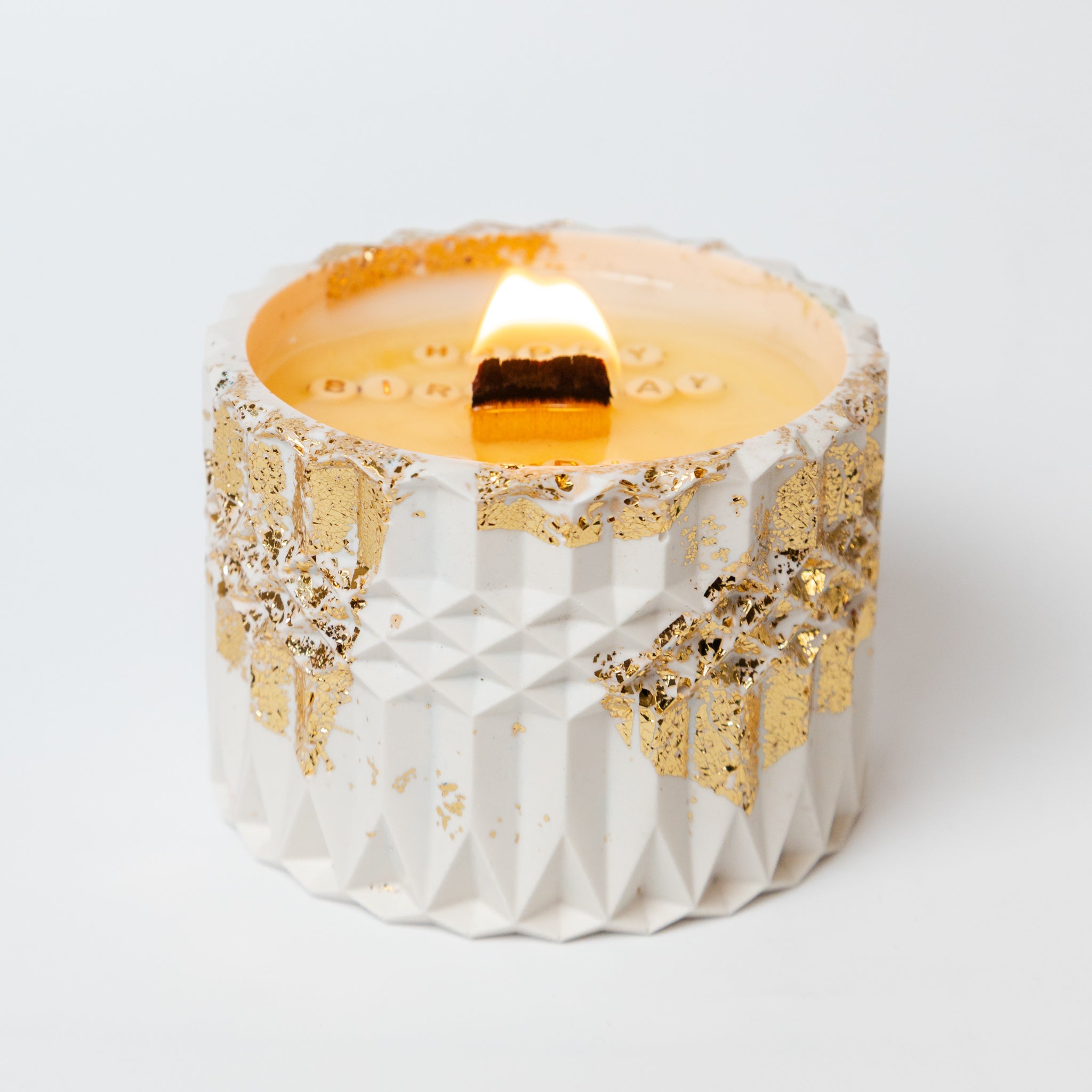 Lit artisan soy wax candle in a gold-flecked pot, creating a warm glow for a personalised birthday gift reveal.