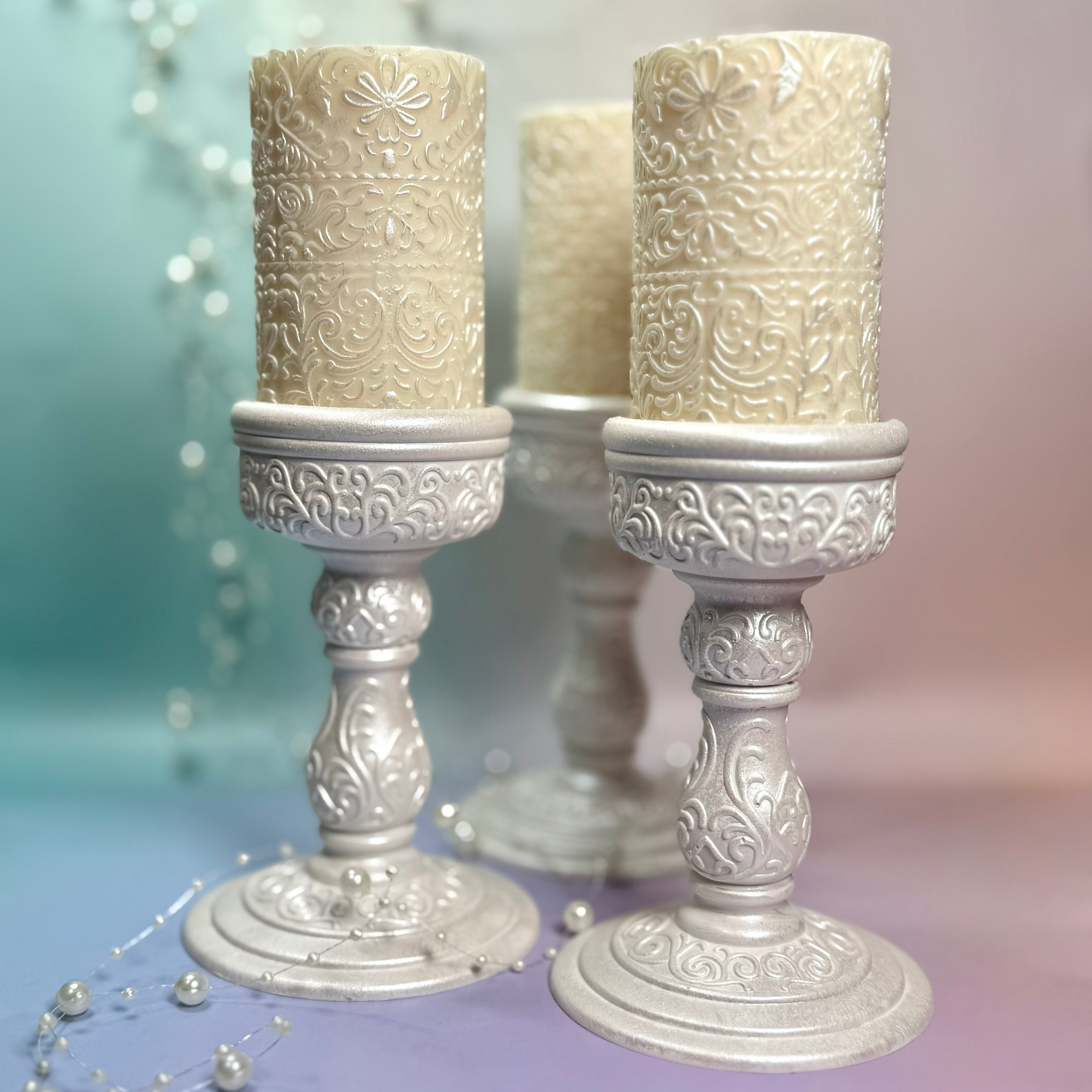 Front view of three Pearl Heritage sets featuring hand-painted pearl-white Jesmonite holders and ornate soy wax pillars.