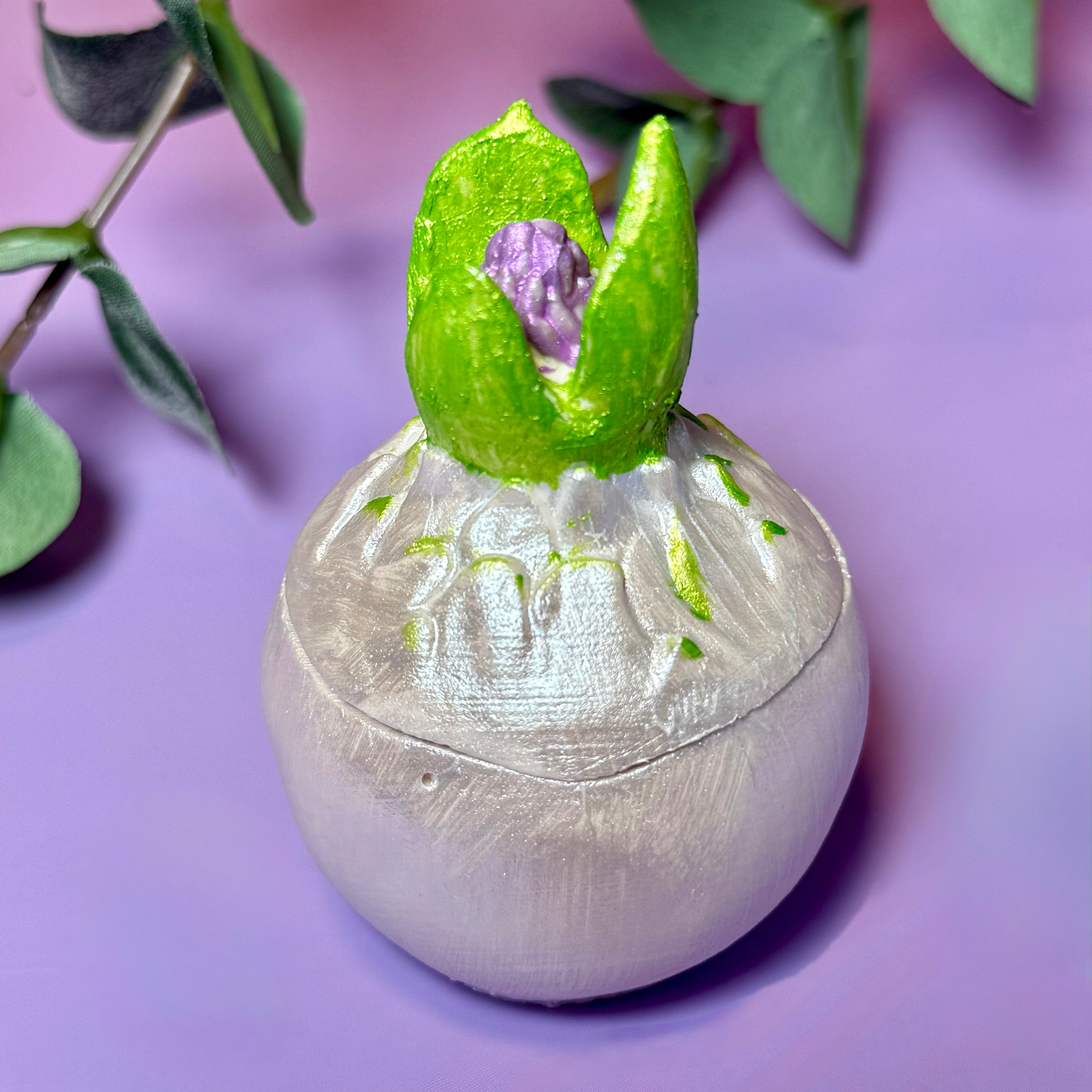 A single hyacinth bulb candle in a shimmering pearl-white finish, showing intricate hand-painted botanical details.