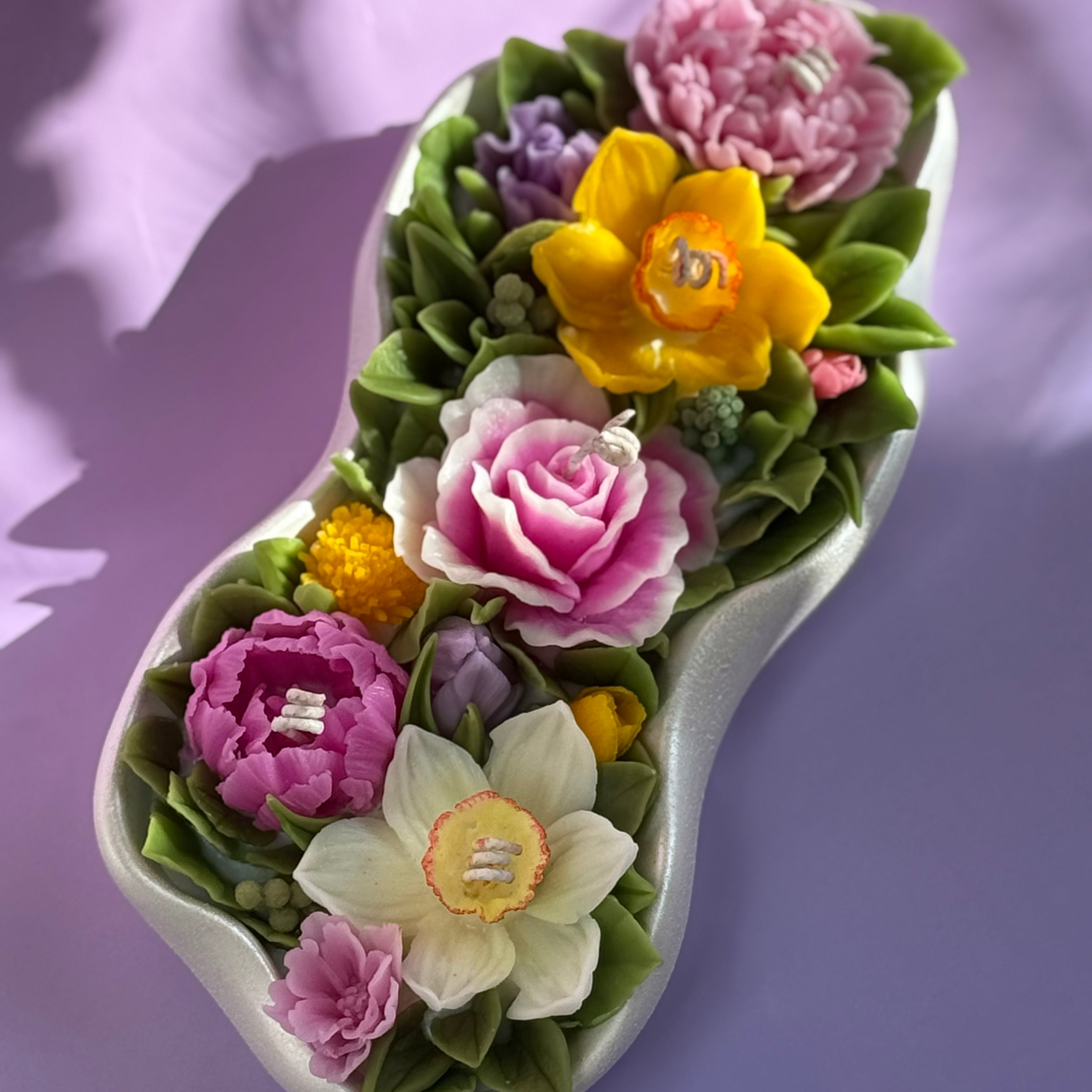 Aerial view of The Grand Floral Haven candle showing a vibrant beeswax garden of pink roses and yellow narcissi in a pearl-white Jesmonite tray.
