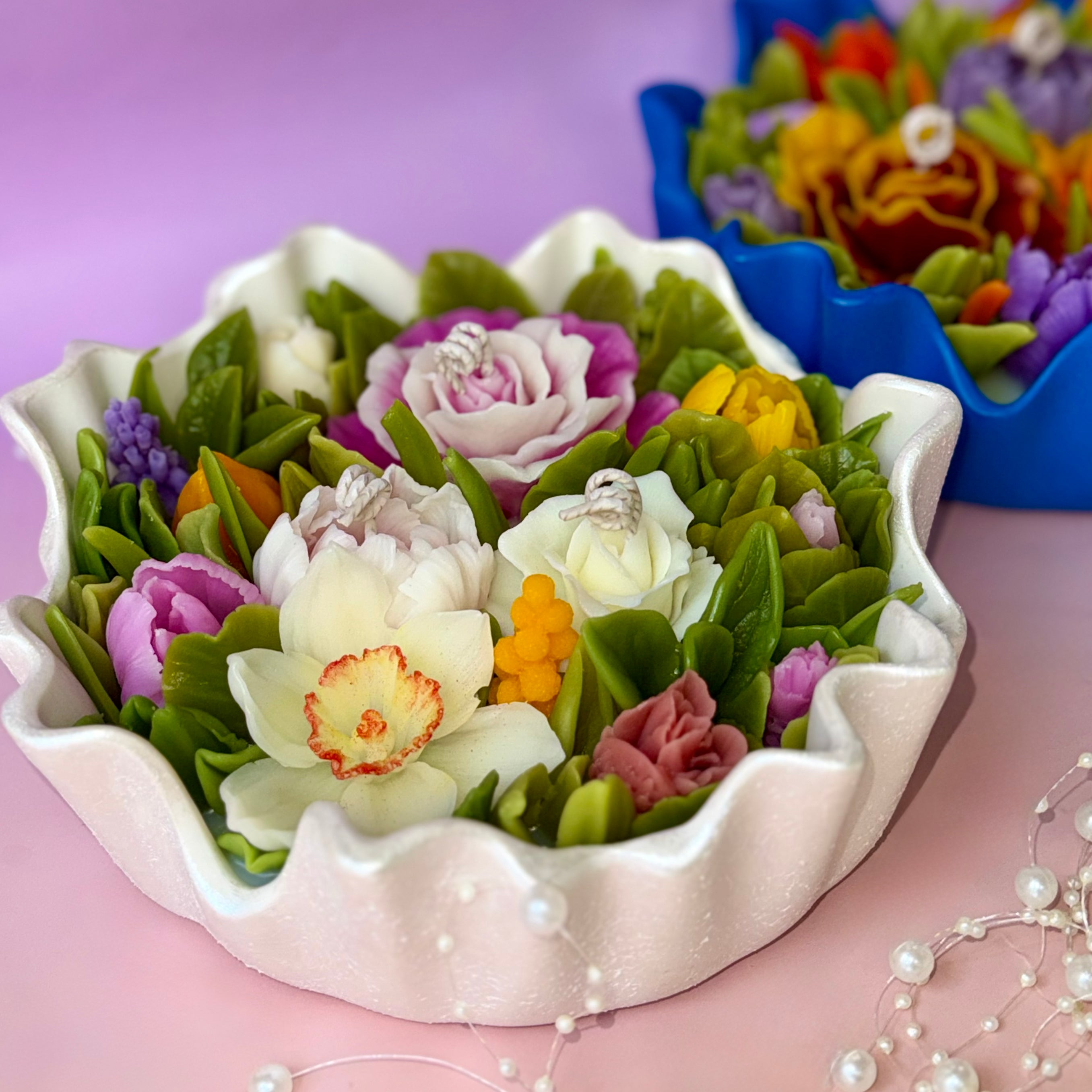 Luxury floral bouquet candle with daffodils and roses in a hand-painted pearl-white fluted bowl.