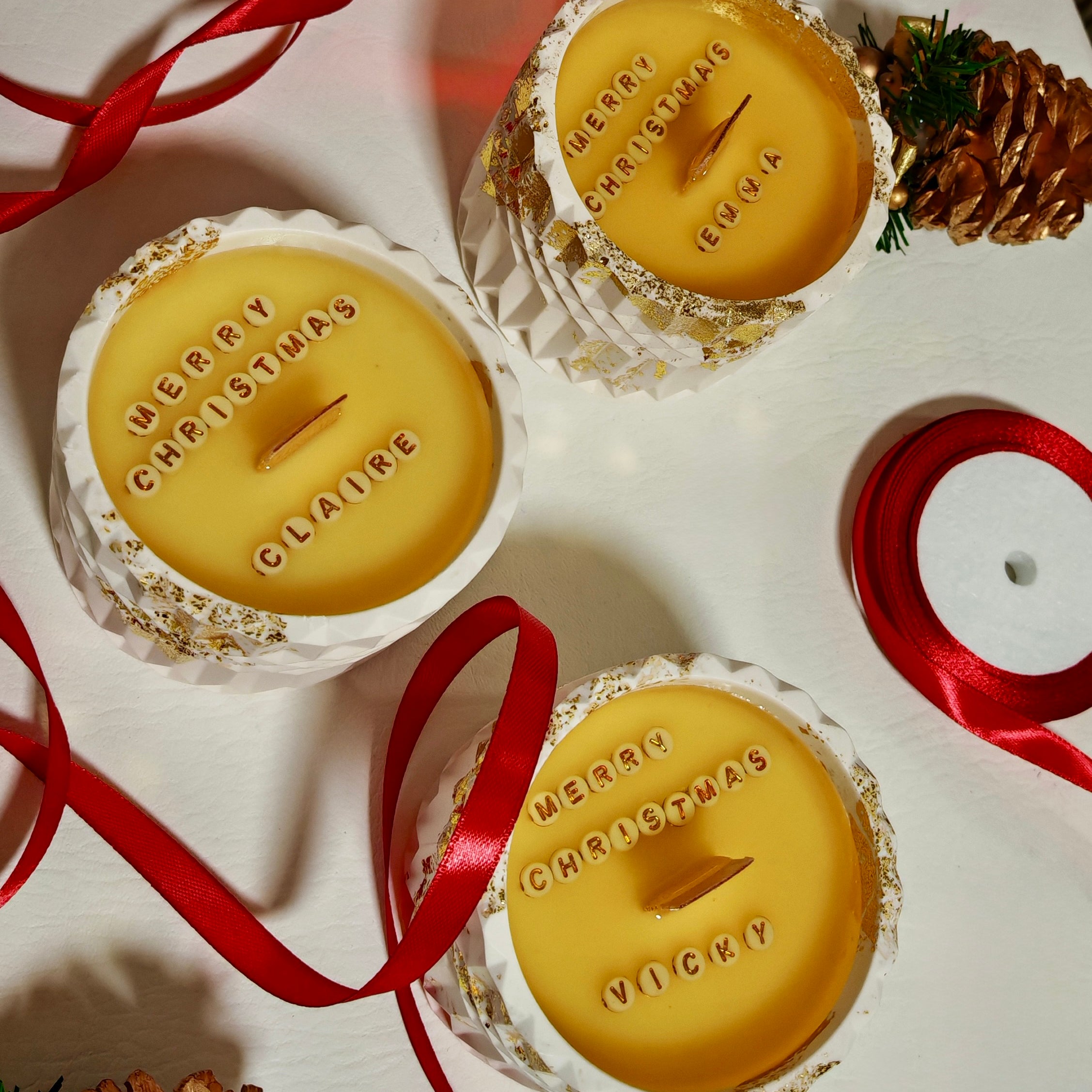 Multiple personalised soy wax candles with different hidden messages, styled with red ribbons as unique Christmas gift ideas.