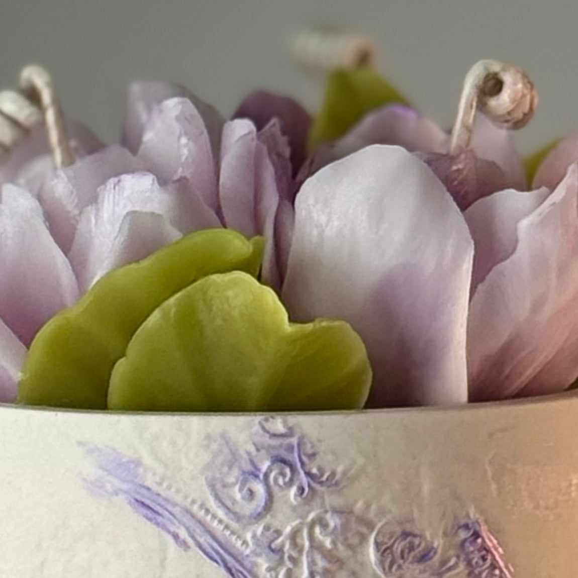 Close-up of the intricately detailed lilac beeswax gardenia flowers and green leaves.