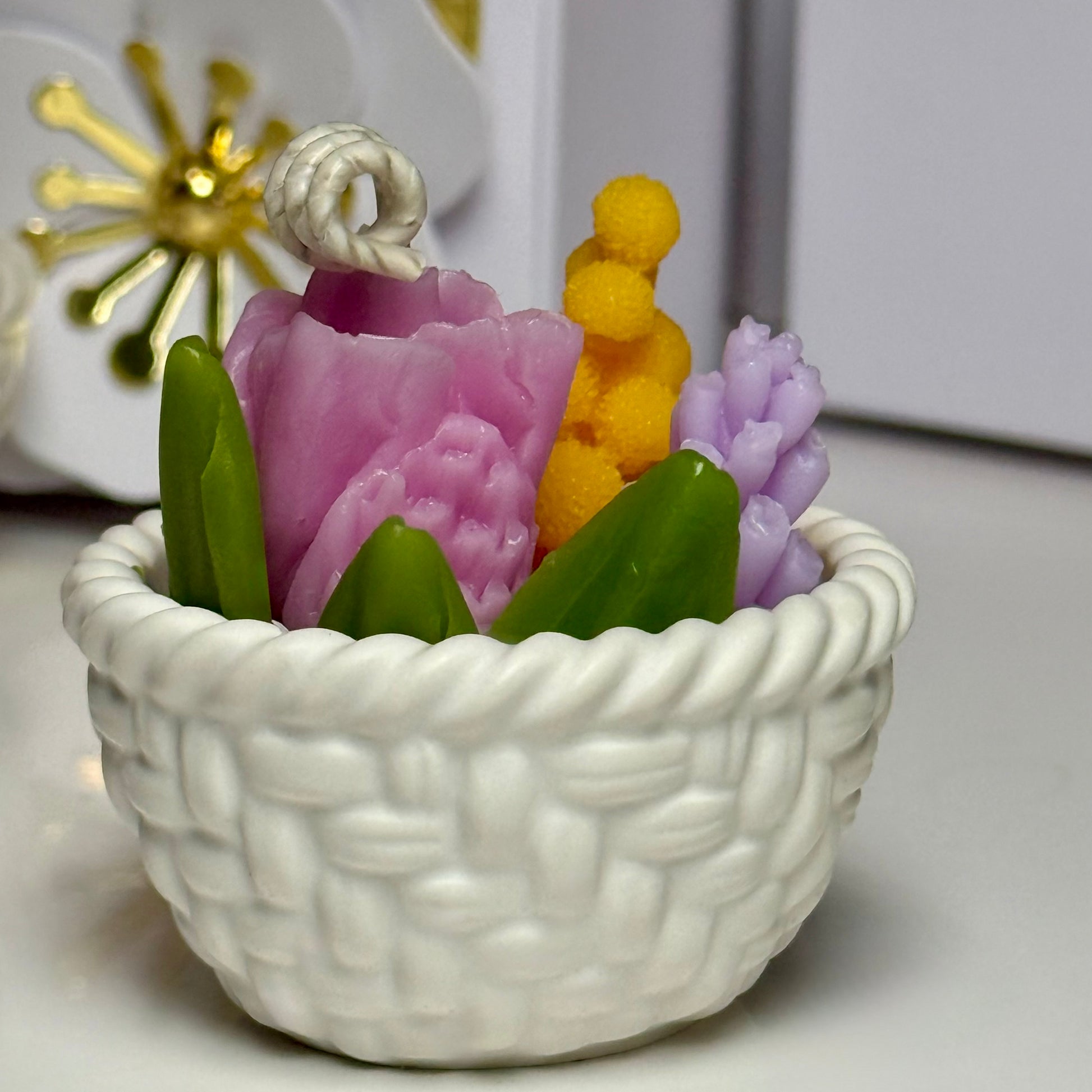 A side profile shot of a single mini Jesmonite basket candle illustrating the smooth cast finish, intricate rope border design, and realistic pink tulip candle wick detail.