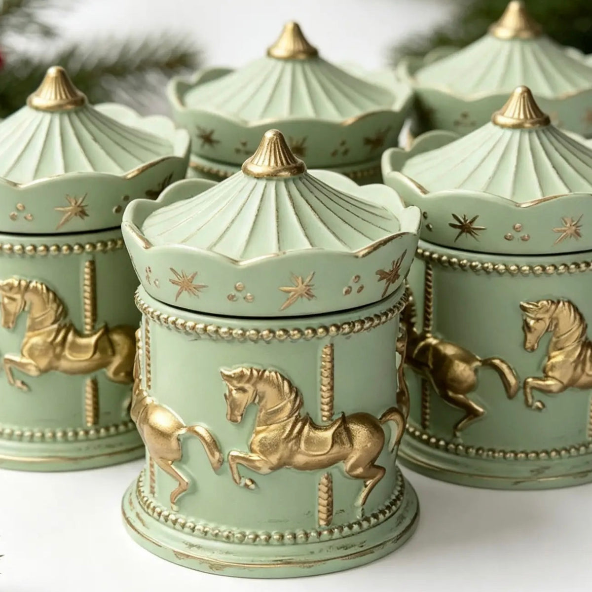 Group of handcrafted sage green and gold carousel candle vessels with lids displayed for Christmas gifts