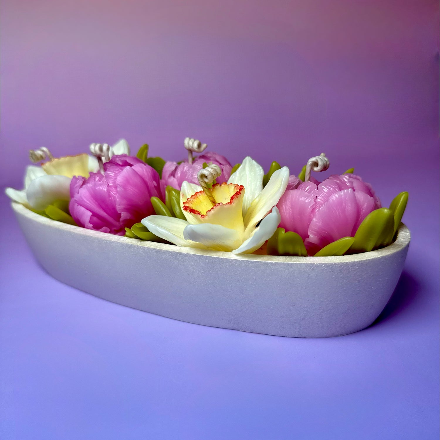 Side-view of a handcrafted 5-wick centrepiece candle featuring pink beeswax peonies and yellow narcissus in a pearl-white hand-painted vessel.