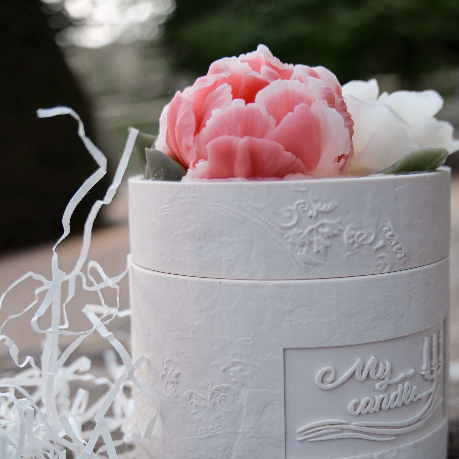 Close-up of a handcrafted pearl-white Jesmonite candle vessel featuring intricate beeswax roses and ranunculus on a decorative lid.