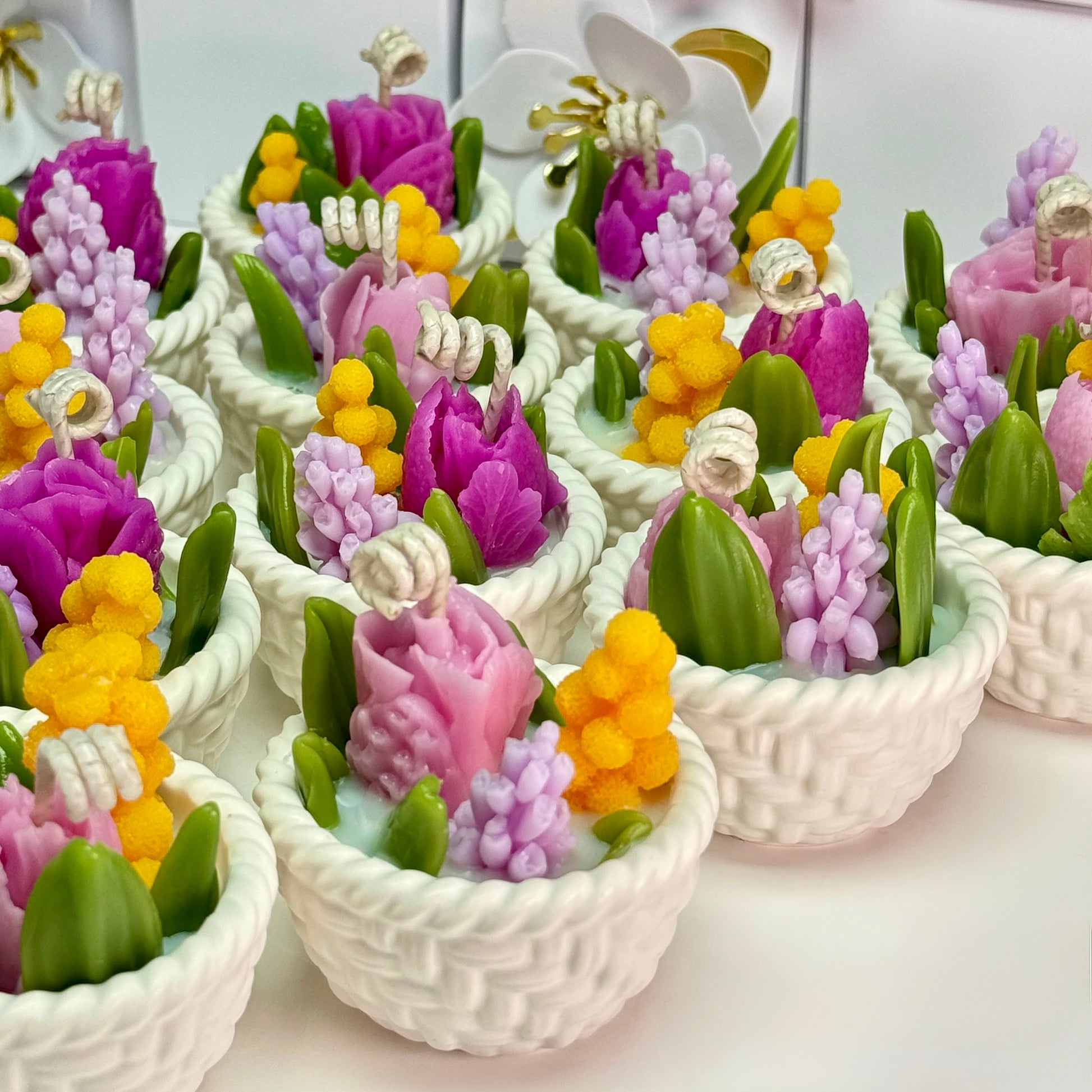 Rows of completed botanical soy wax candles in hand-cast Jesmonite baskets arranged neatly on a table for a wholesale bulk wedding favour order.