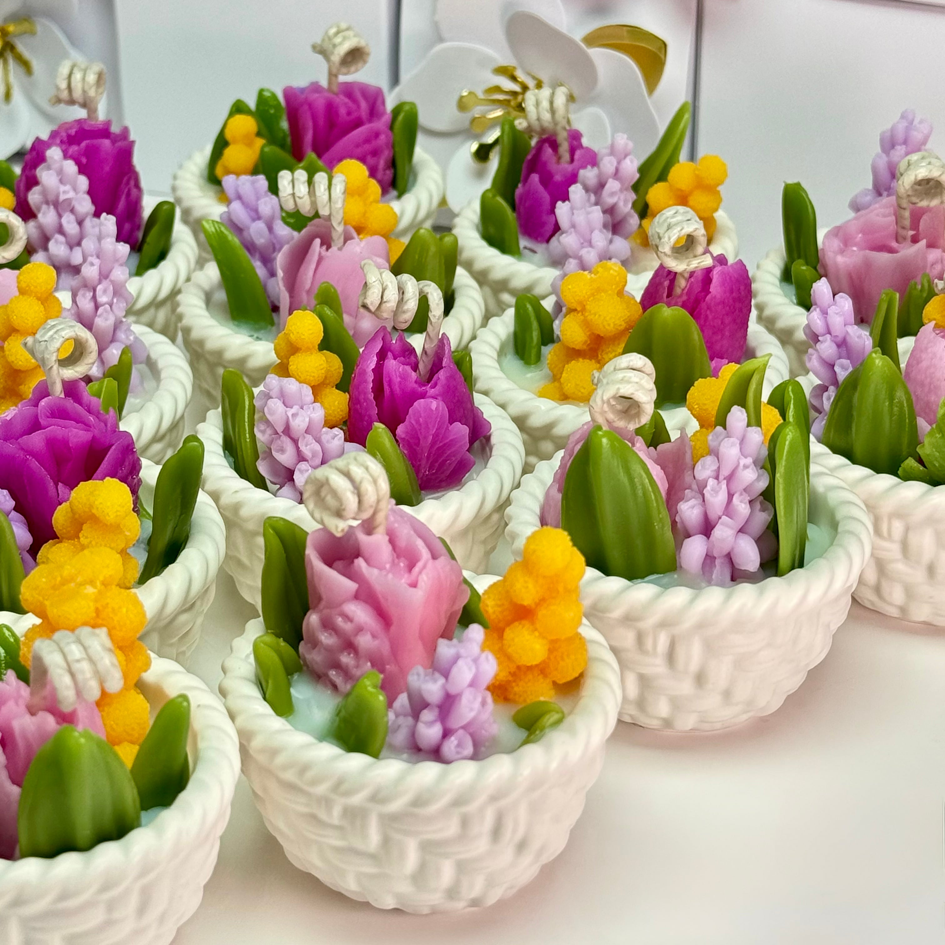 Rows of completed botanical soy wax candles in hand-cast Jesmonite baskets arranged neatly on a table for a wholesale bulk wedding favour order.