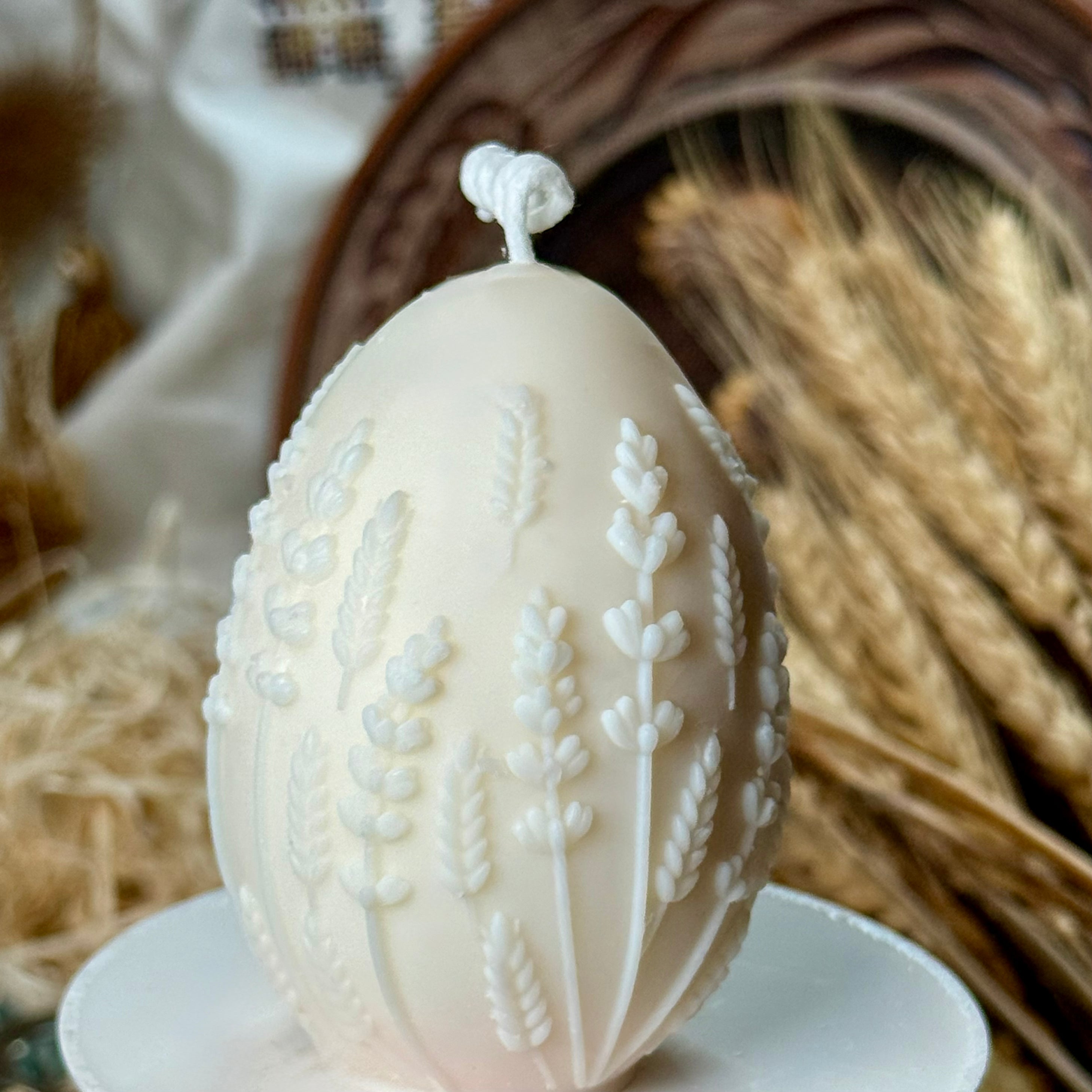 Macro presentation of the unpainted cream-white botanical egg candle, highlighting the precise, crisp lines of the hand-poured soy wax harvest relief details.
