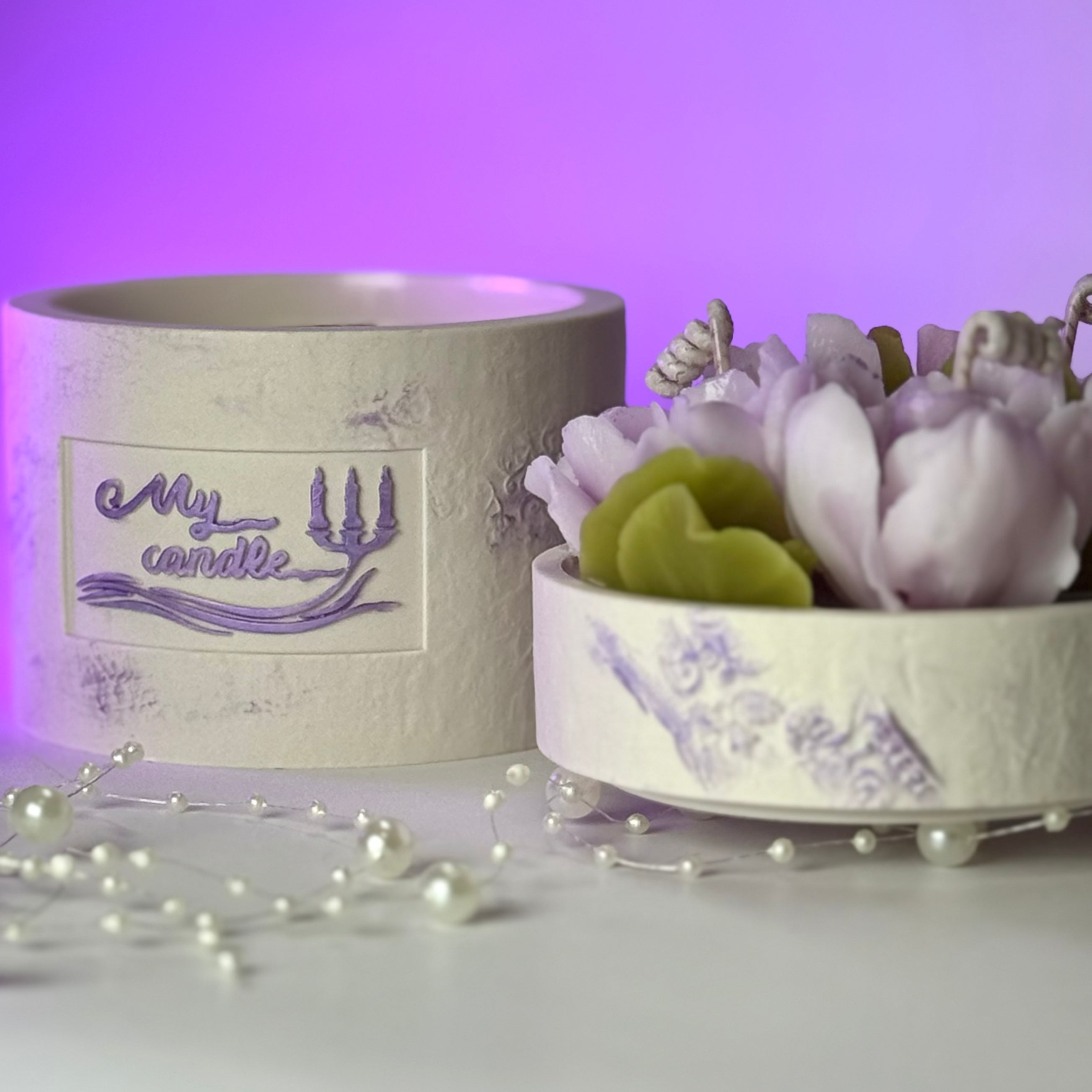 Side view of the unique in-house designed lilac gardenia candle next to its handcrafted purple-textured base.