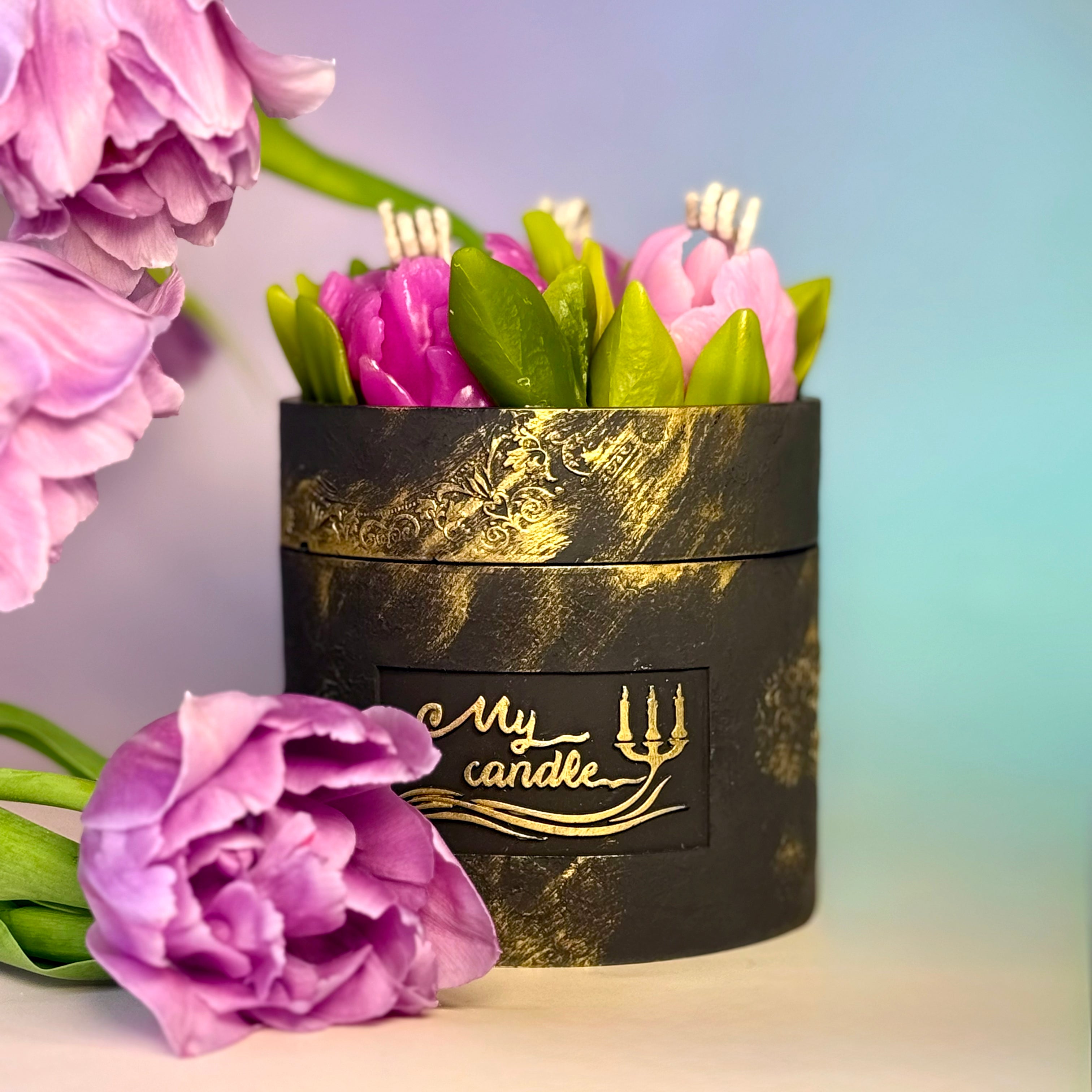 Premium botanical candle gift box in black and gold textured Jesmonite, showcasing a detailed 3-wick lid filled with handcrafted purple wax flowers and green leaves.