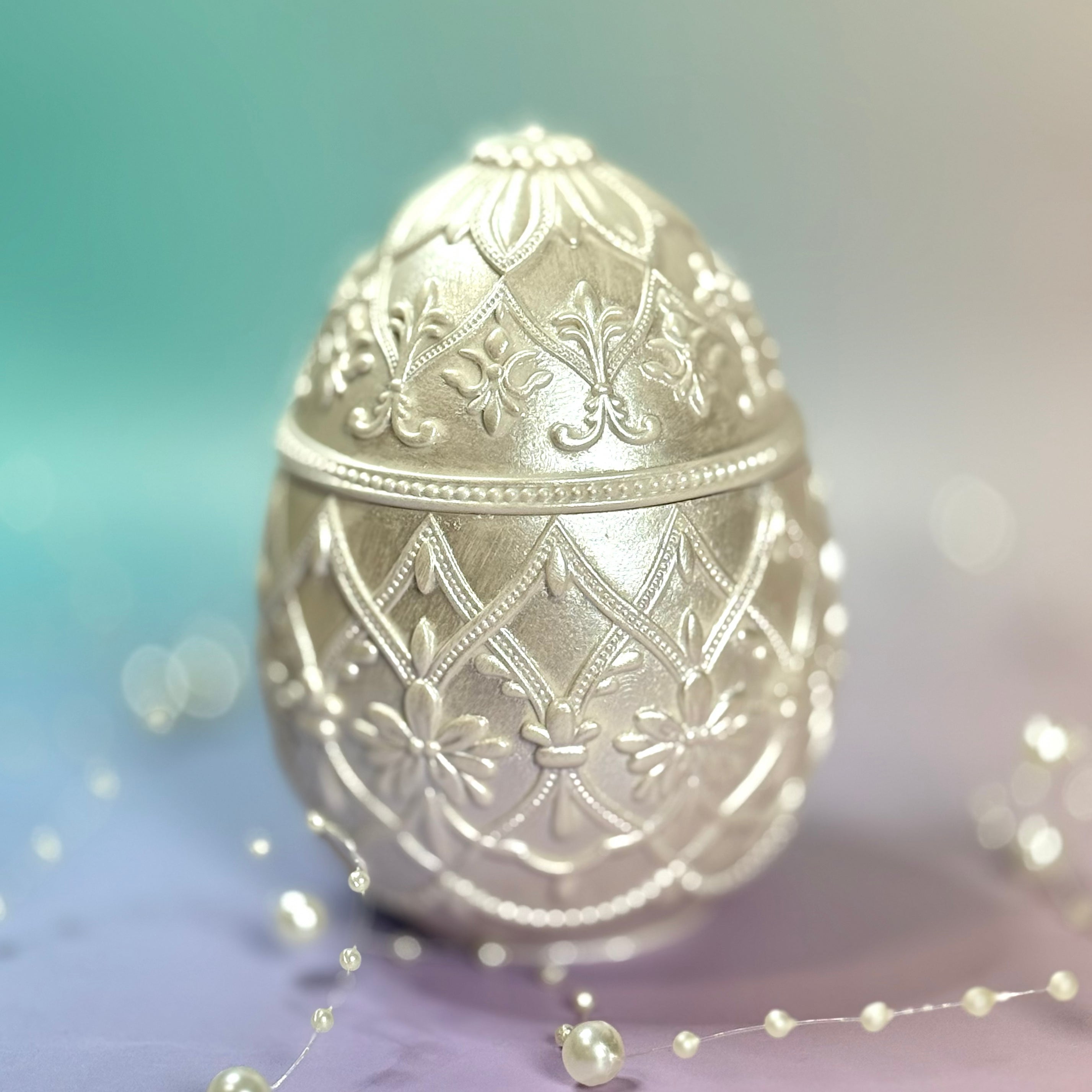 Elegant pearlescent classic white baroque style Easter egg lidded candle container sitting on a pastel surface with glowing bokeh lights.