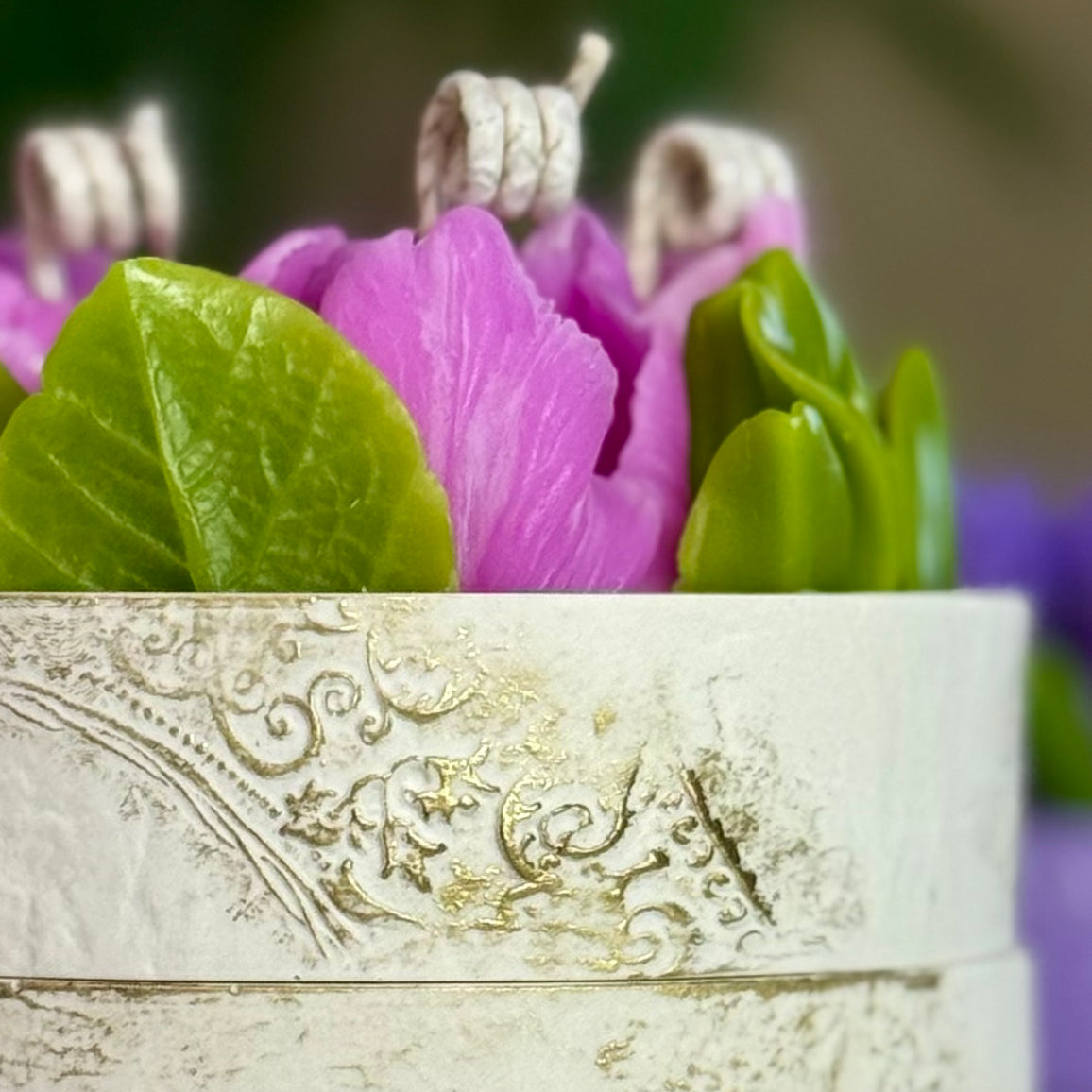 Macro shot highlighting the intricate details of handcrafted pink beeswax peony leaves on a luxury floral candle with gift box.
