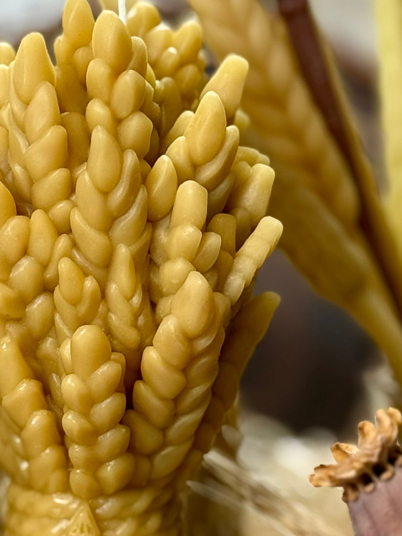 A highly detailed macro close-up highlighting the crisp, realistic 3D textures of the individual wheat ears on the hand-poured natural beeswax sculptural candle.