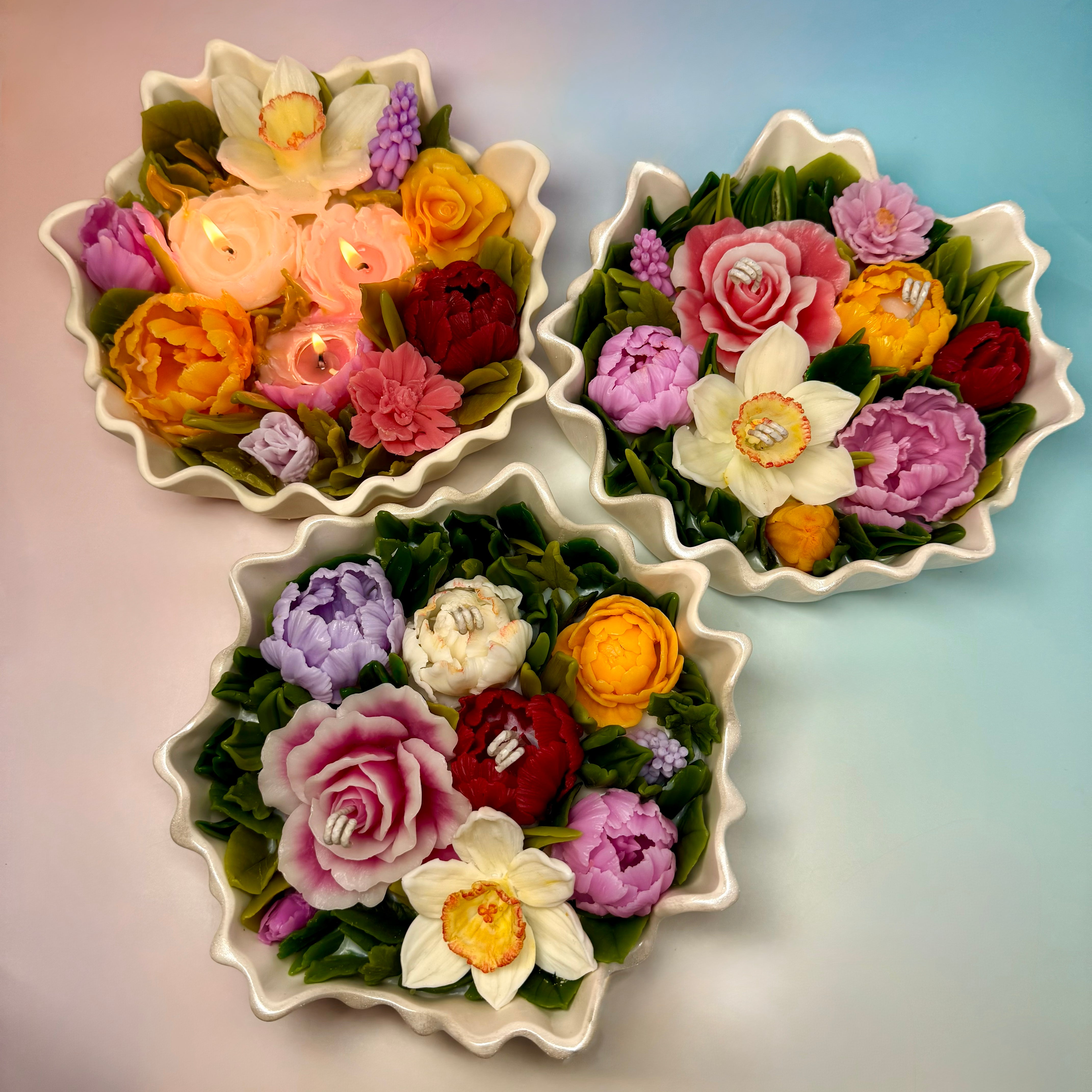 A collection of handmade flower candles with vibrant multi-coloured blooms, showcasing the artisan beeswax craftsmanship.