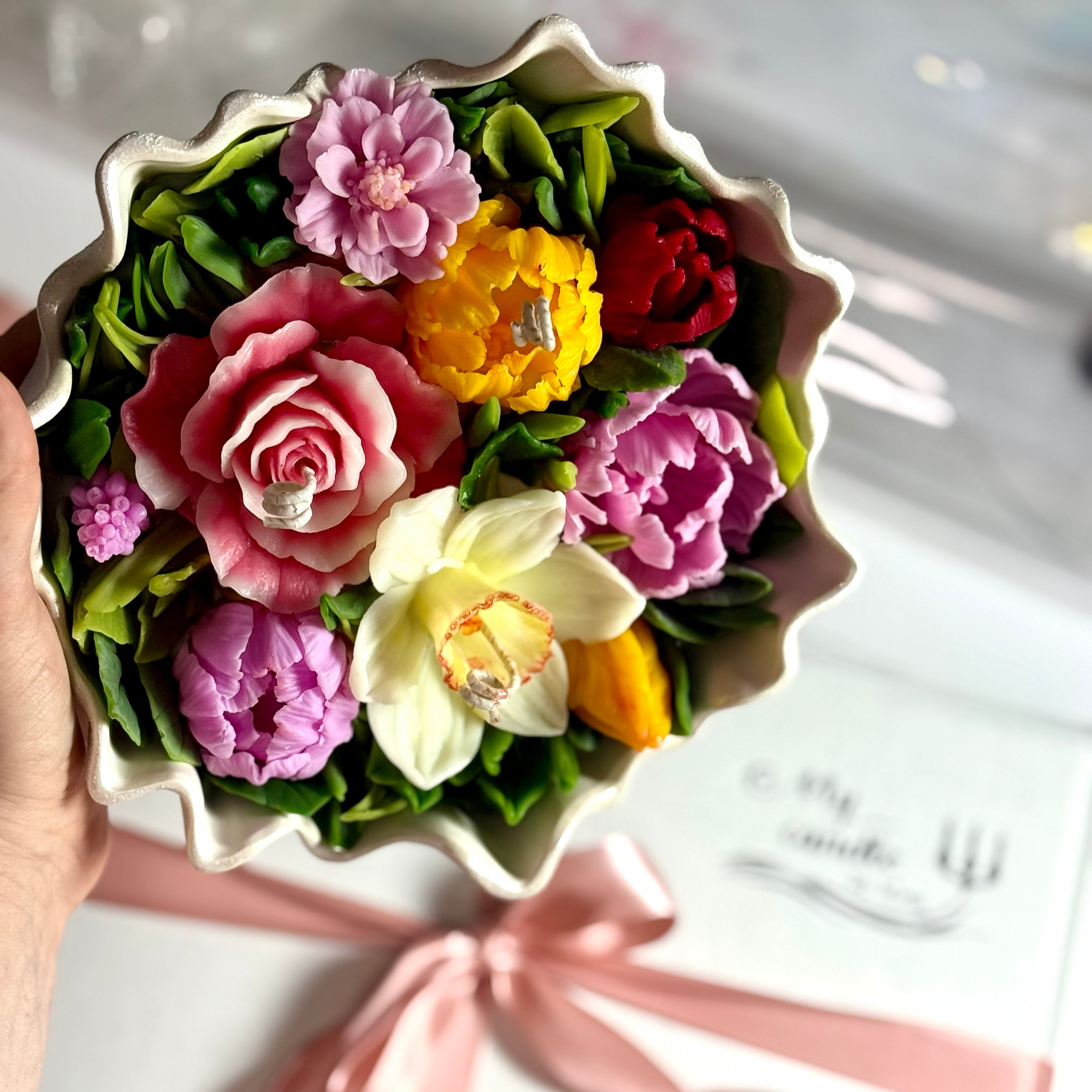 Holding a completed floral bouquet candle to show the impressive scale and intricate petal detail.