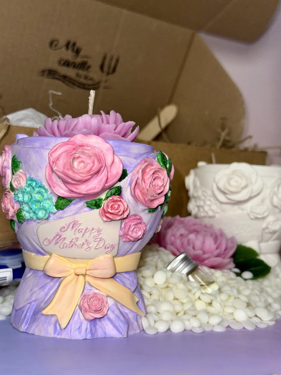 A finished and beautifully hand-painted purple bouquet candle container with pink roses and a "Happy Mother's Day" ribbon, filled with soy wax and topped with a large pink beeswax flower.