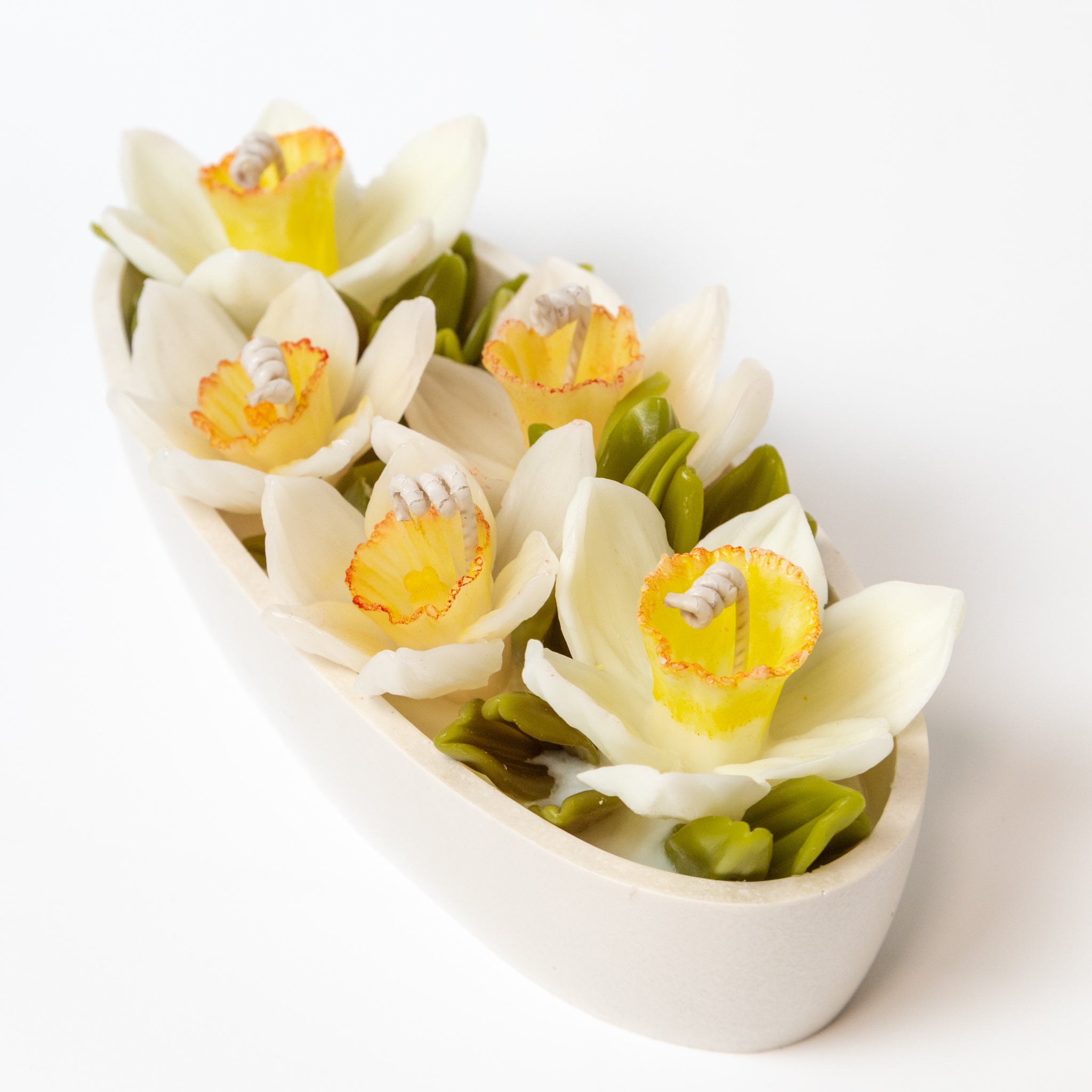 Detailed view of handcrafted white beeswax narcissus flowers on a white background.