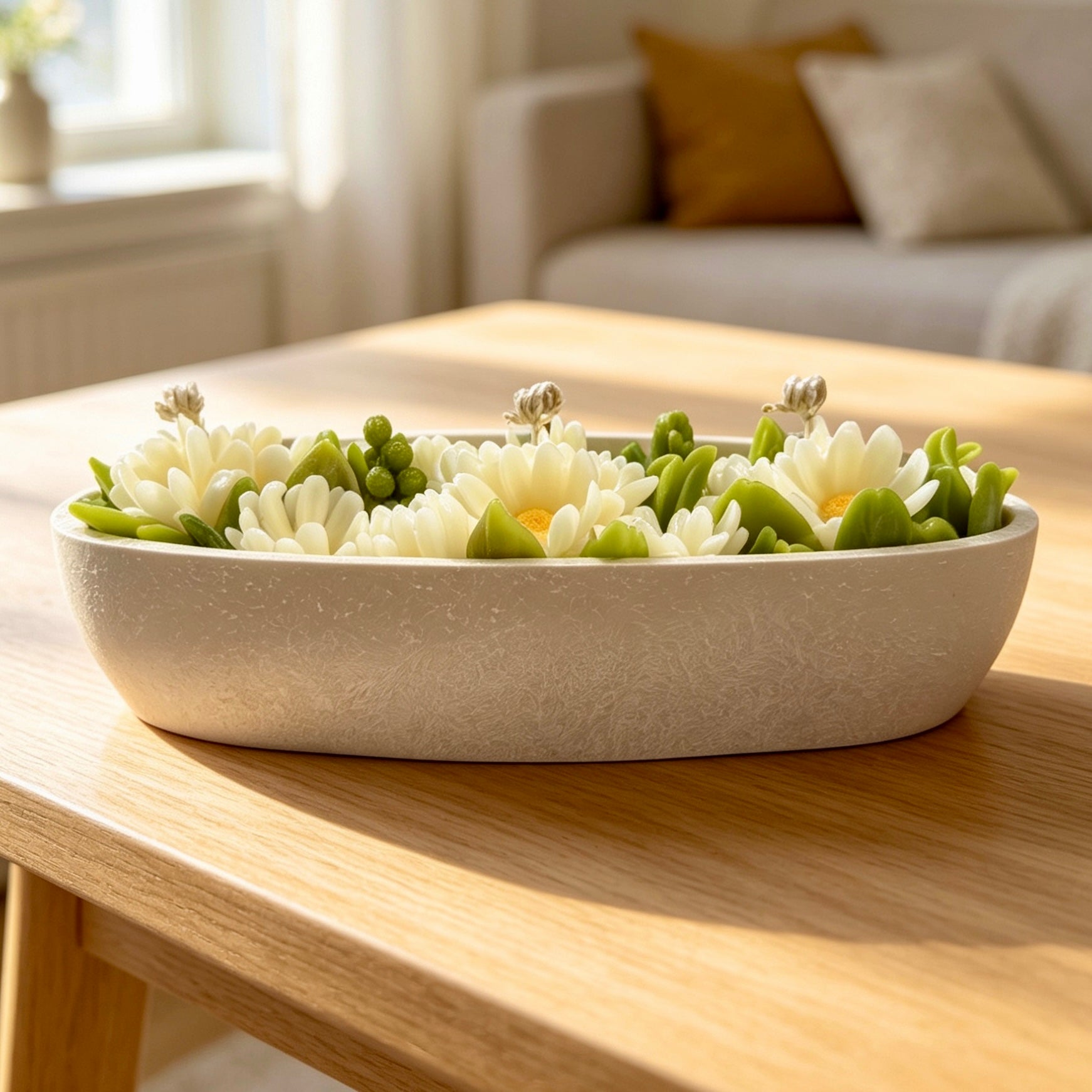 Side view of an oval chamomile flower bouquet candle on a coffee table, styled as luxury home decor in a bright, modern living room.