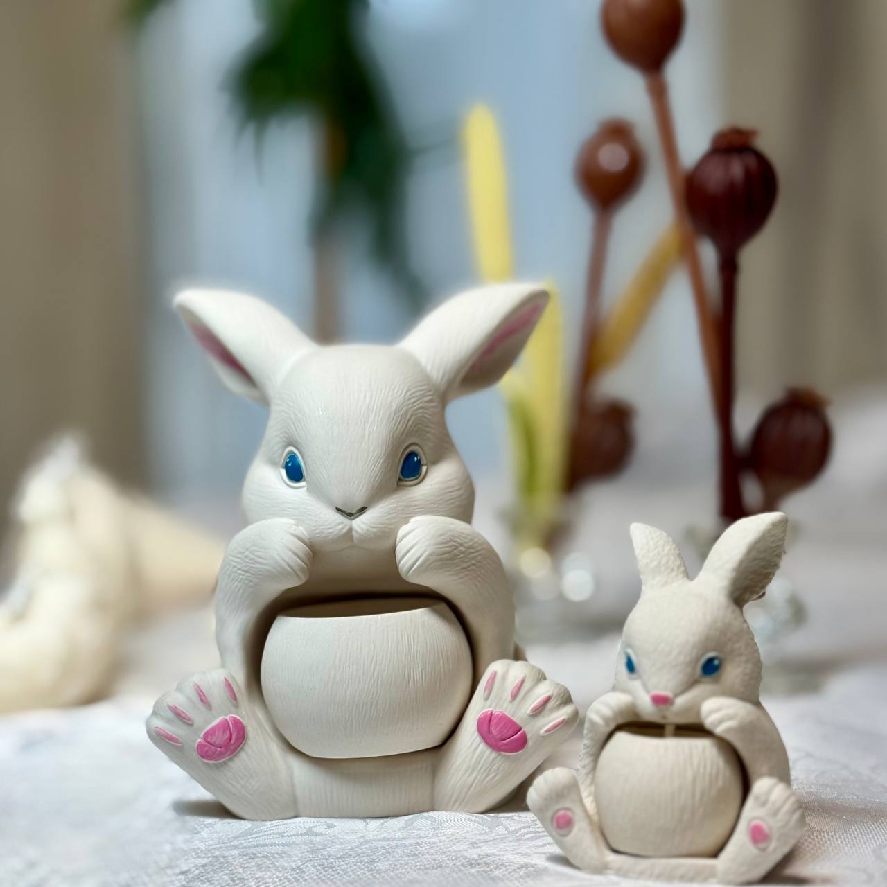 A large and a small handcrafted Jesmonite Easter bunny arranged together on a table, showcasing the hand-painted details with pink paws and blue eyes for spring home decor.