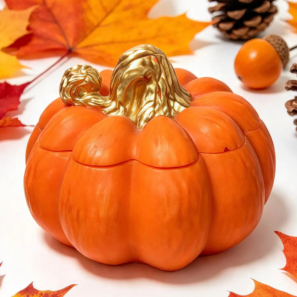 Side view of handcrafted orange pumpkin candle container with gold-painted stem on white background