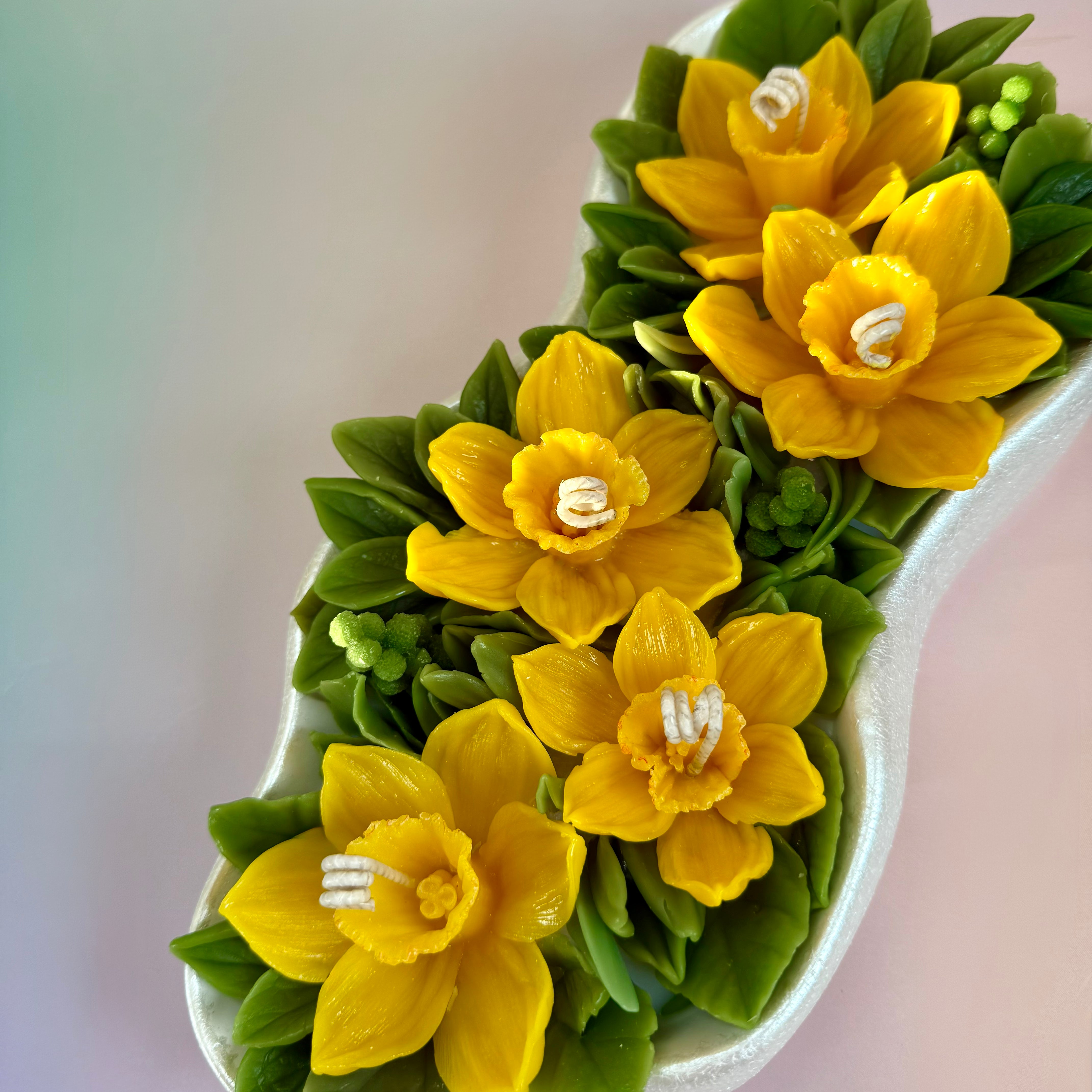 Side view of the wave-shaped Jesmonite boat tray filled with botanical wax daffodils.