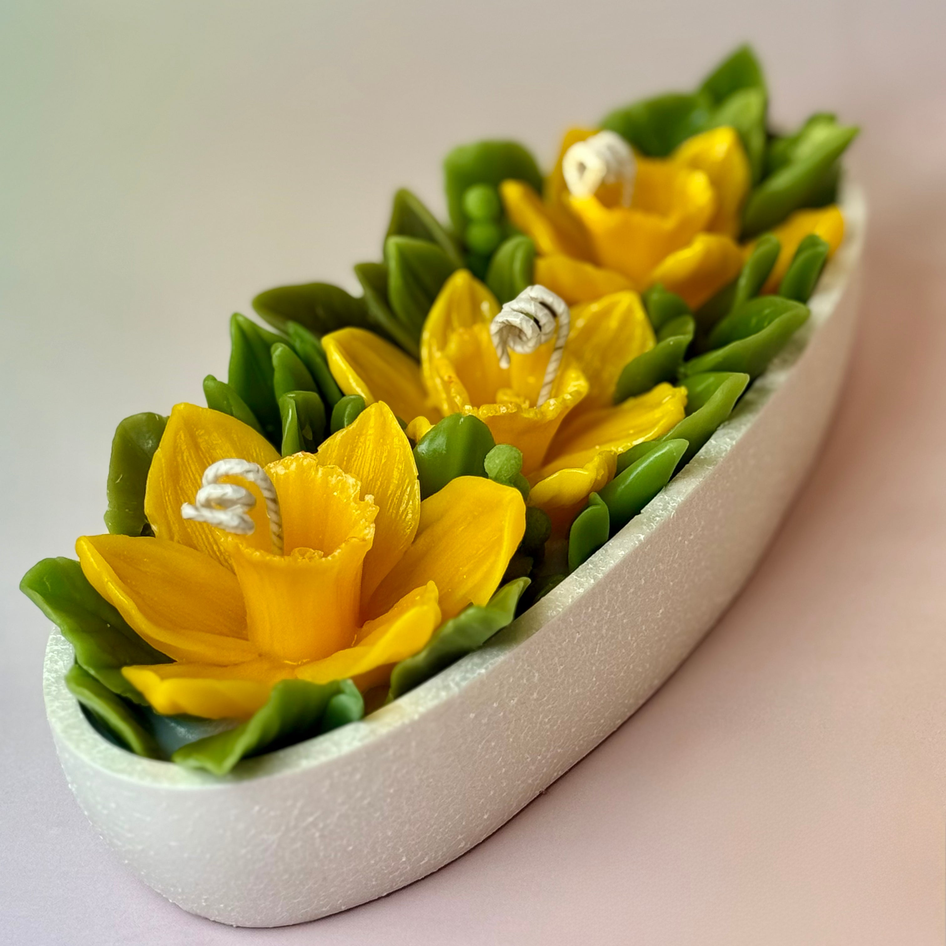 Perspective view of the daffodil floral centrepiece candle on a soft pastel background.