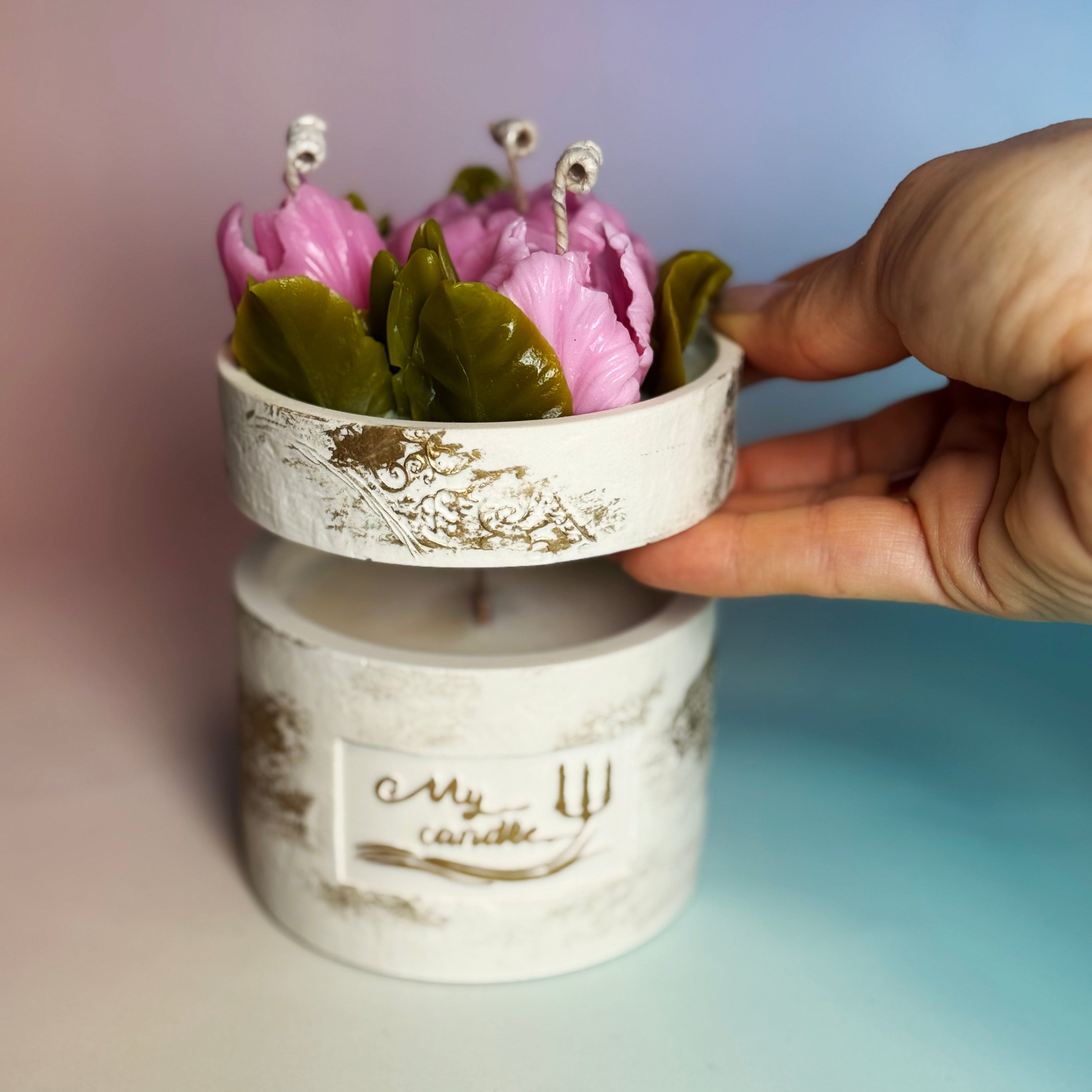Hand lifting the floral topper to reveal the clean-burning soy wax base underneath.