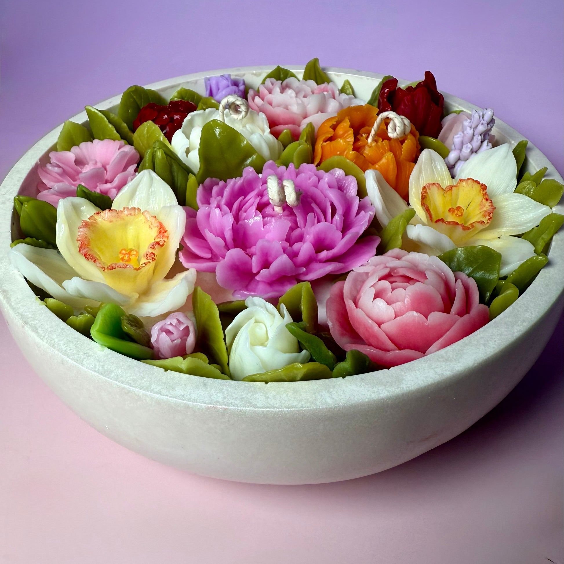 Elegant flower candle arrangement in a pearl-white stone-textured vessel, showcasing the dense botanical detail of this centrepiece floral candle.