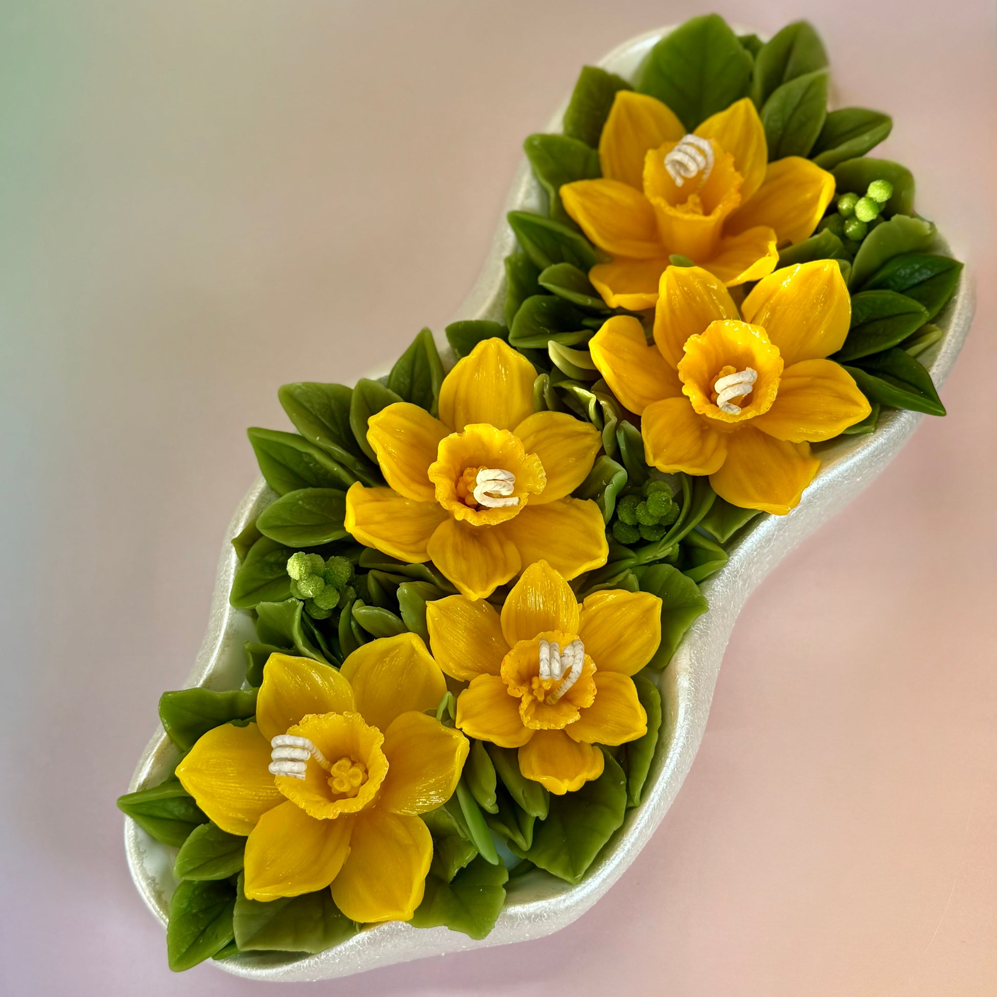Large 30cm floral candle centrepiece featuring yellow beeswax daffodils in a pearl white tray.