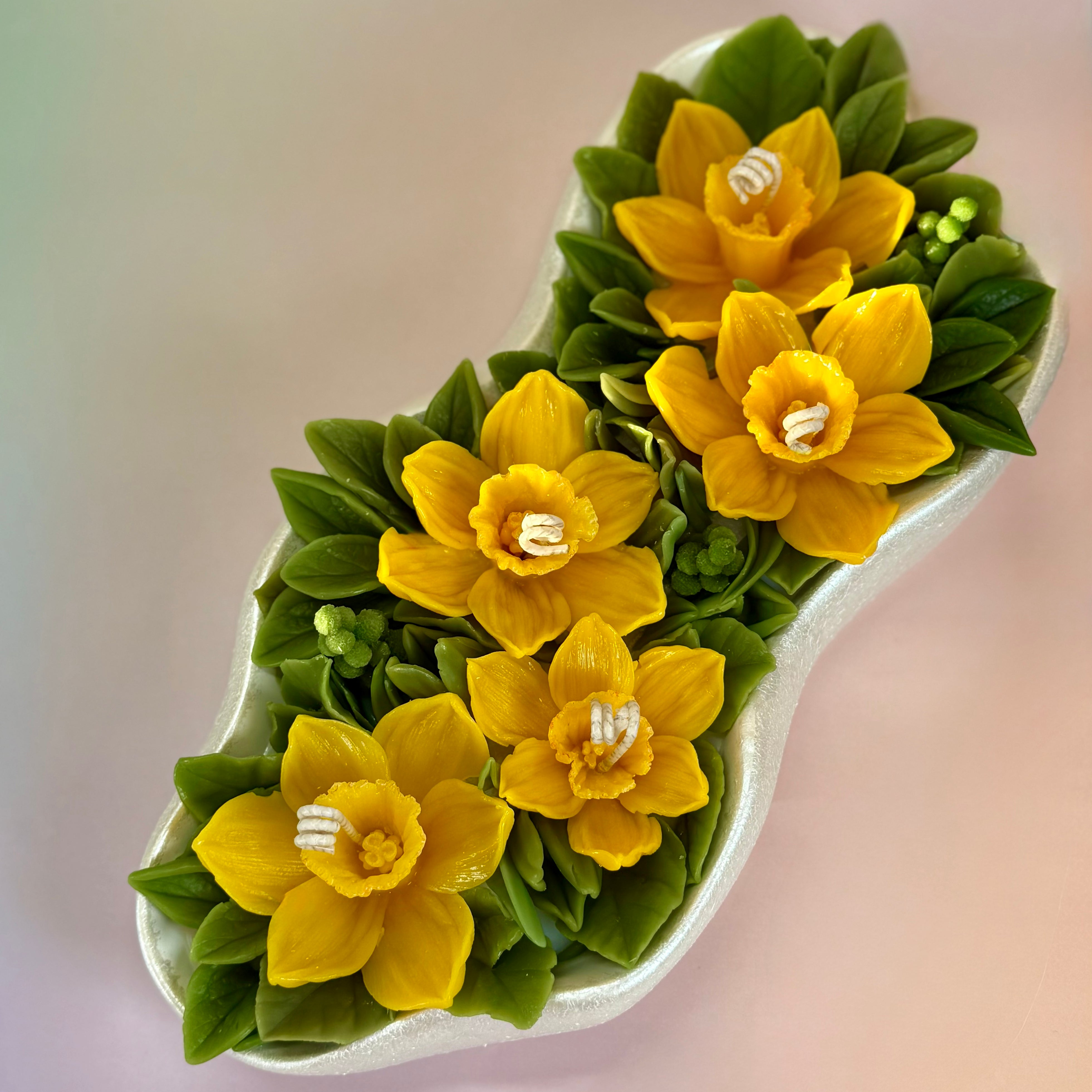 Large 30cm floral candle centrepiece featuring yellow beeswax daffodils in a pearl white tray.