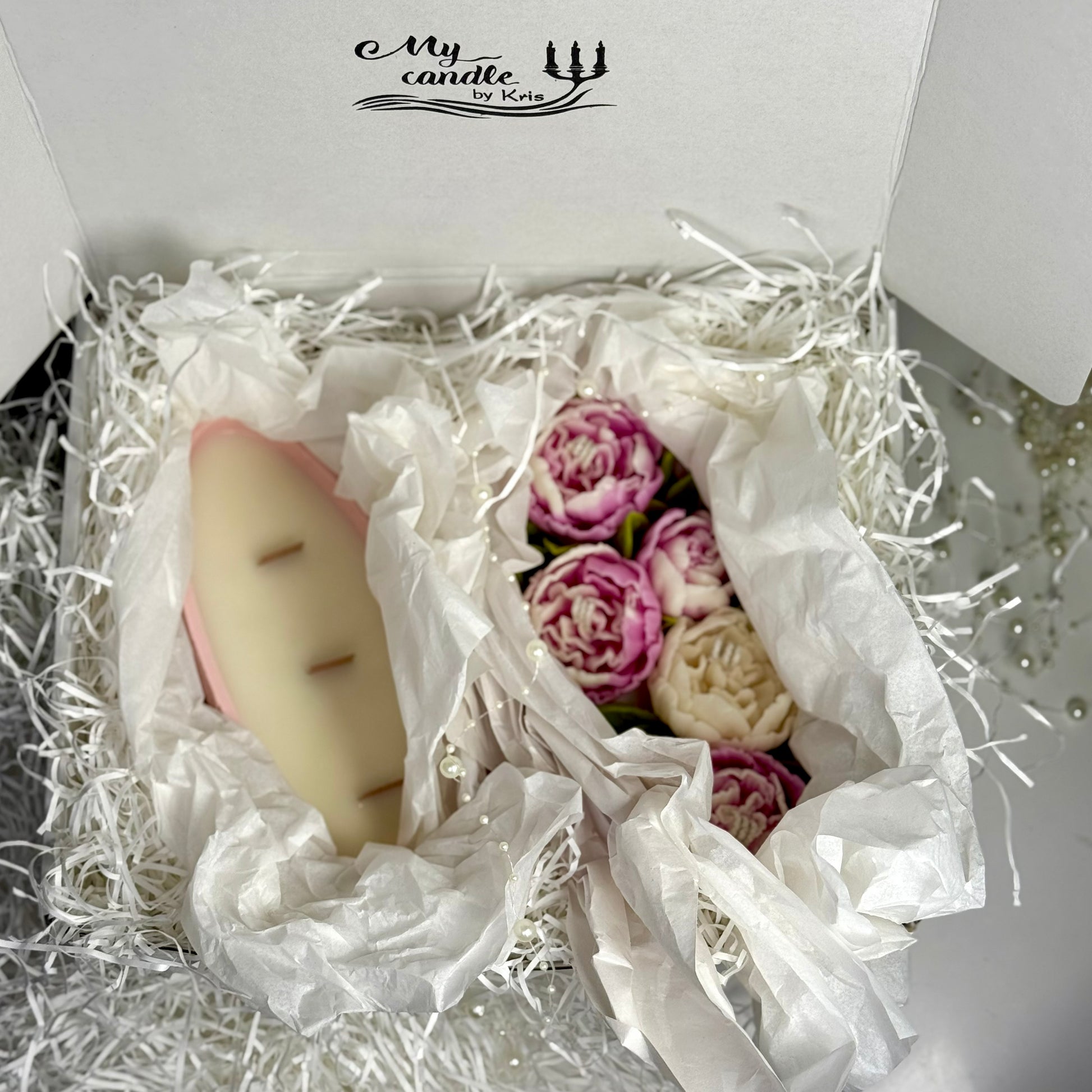 Premium white gift box opened to reveal a two-part refillable floral candle nestled in elegant white shredding with delicate pearl details.