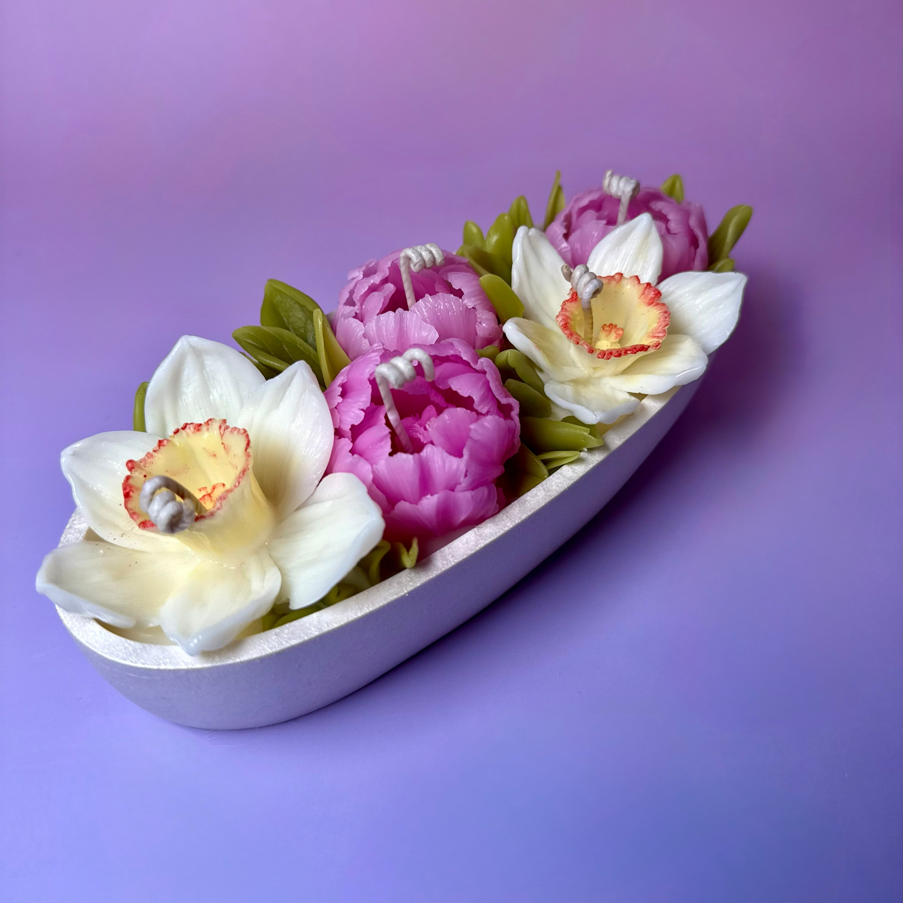 High-angle view of a luxury flower meadow candle featuring hand-sculpted pink beeswax peonies and white narcissus in a pearl-white Jesmonite vessel.