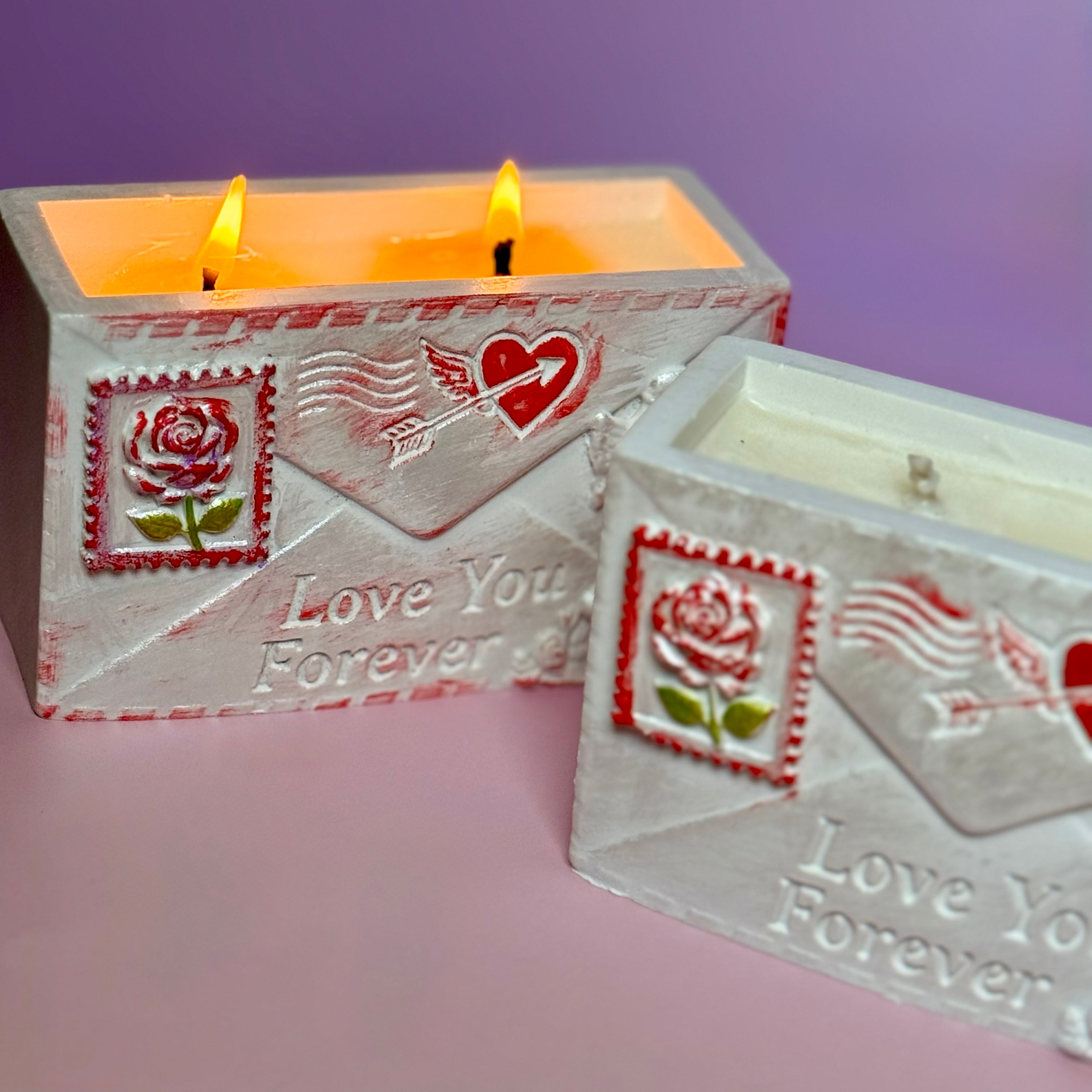 Close-up macro view of a glowing golden wax pool and two lit wicks inside the handcrafted Jesmonite envelope container, emphasizing the warm romantic ambiance.