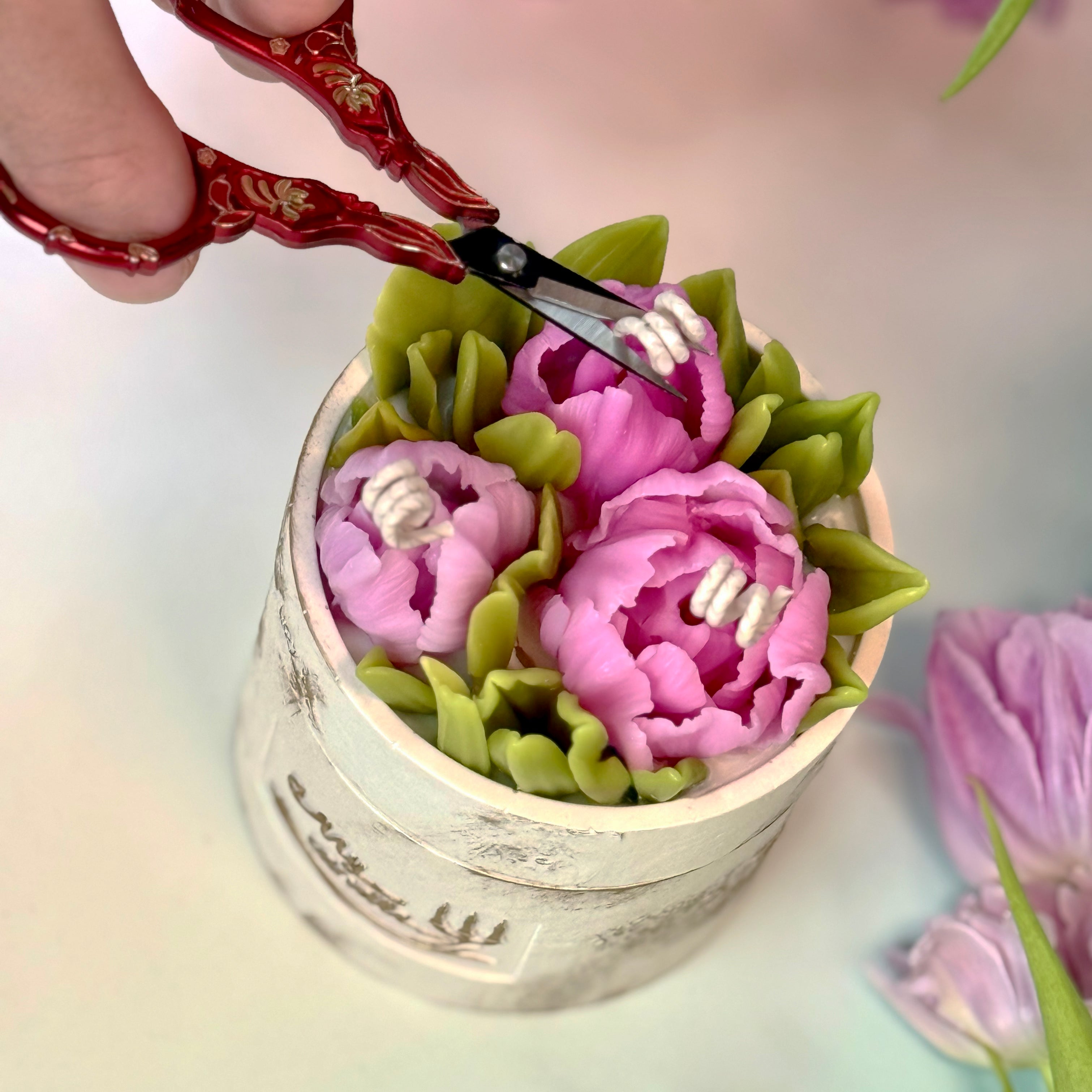 Close-up of a premium botanical candle arrangement showcasing intricately detailed 3D beeswax peony tulips and delicate green leaves