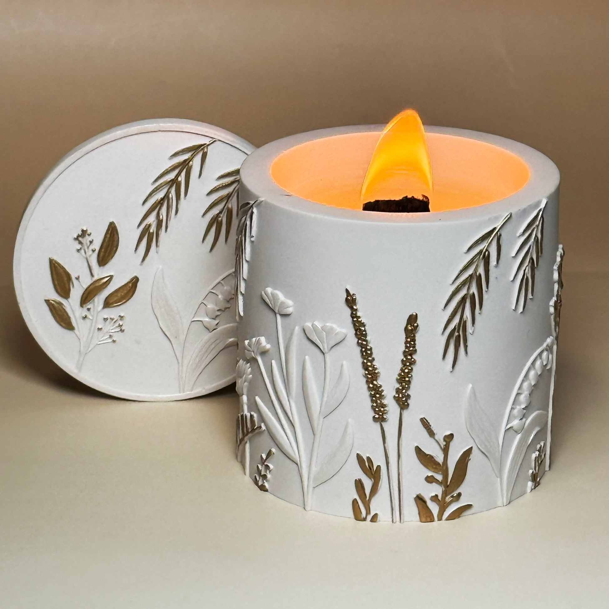 Luxury Jesmonite candle with botanical relief and hand-painted gold details, lit with a wooden wick