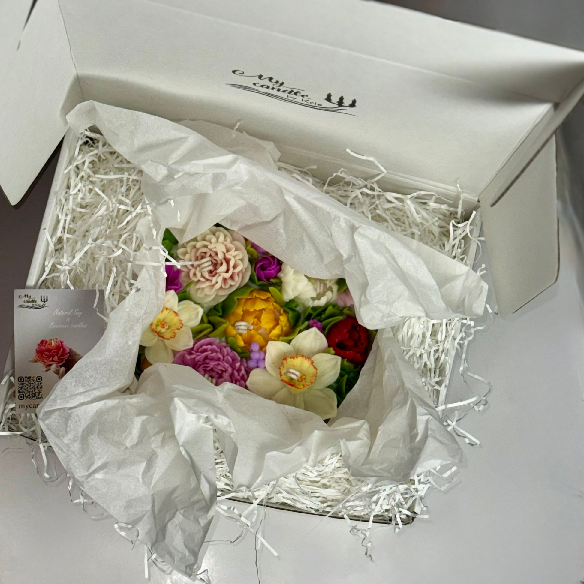 Unboxing experience showing the floral candle safely packed in white protective paper.
