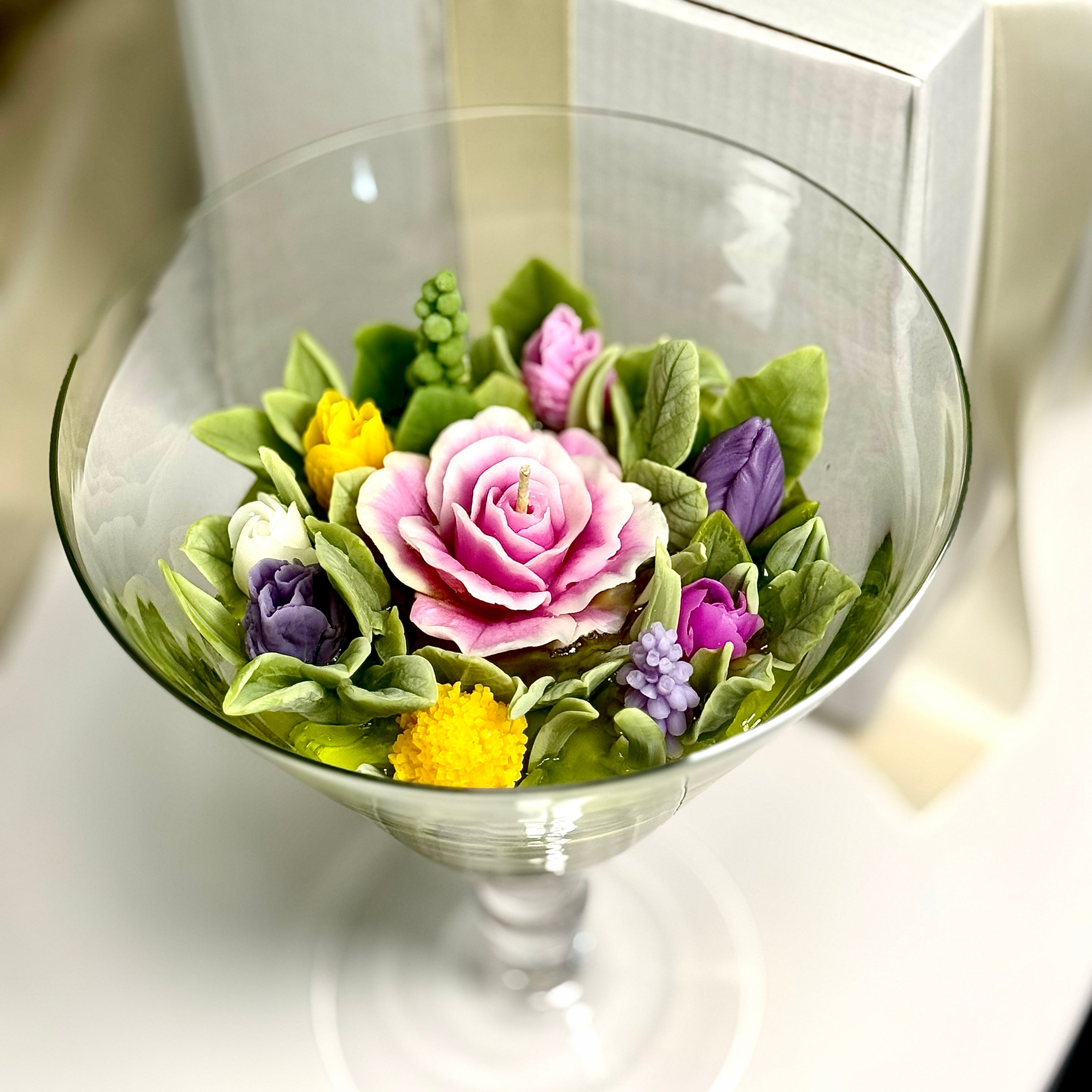 Perfect overhead view of a premium 3D beeswax floral candle set in a round glass cone vase, showcasing detailed multi-coloured spring blooms and wick with gift box.