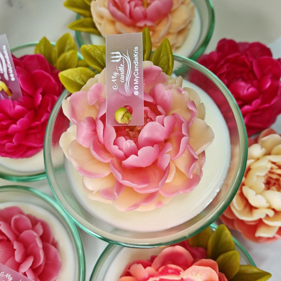 Top down view of a large, realistic hand-moulded beeswax peony in a glass vessel.