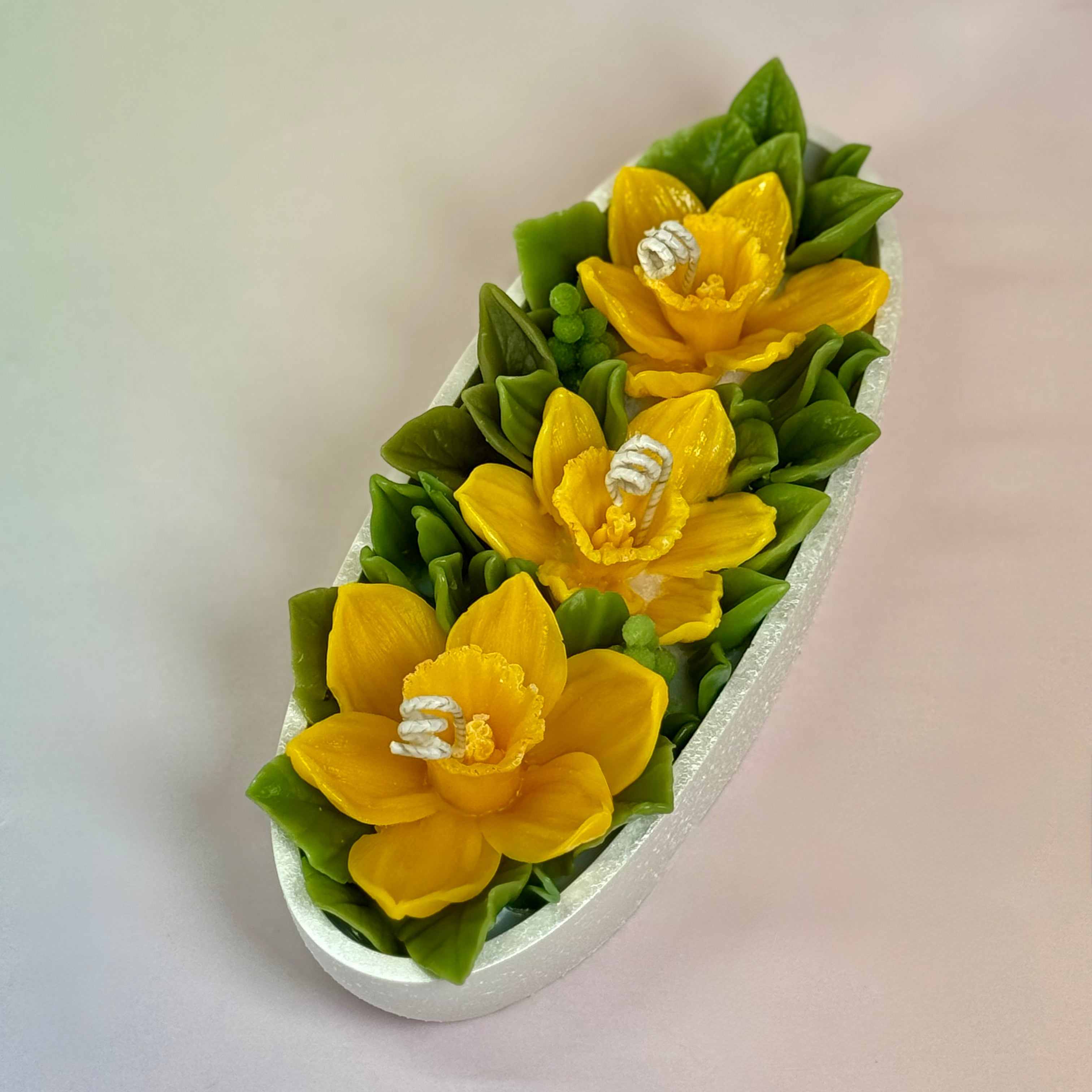 Three realistic beeswax daffodils in a pearl white Jesmonite boat tray, 21cm long.
