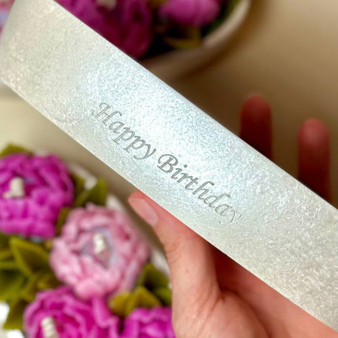 Close-up of 'Happy Birthday' custom engraving on a shimmering pearl-white Jesmonite candle holder.