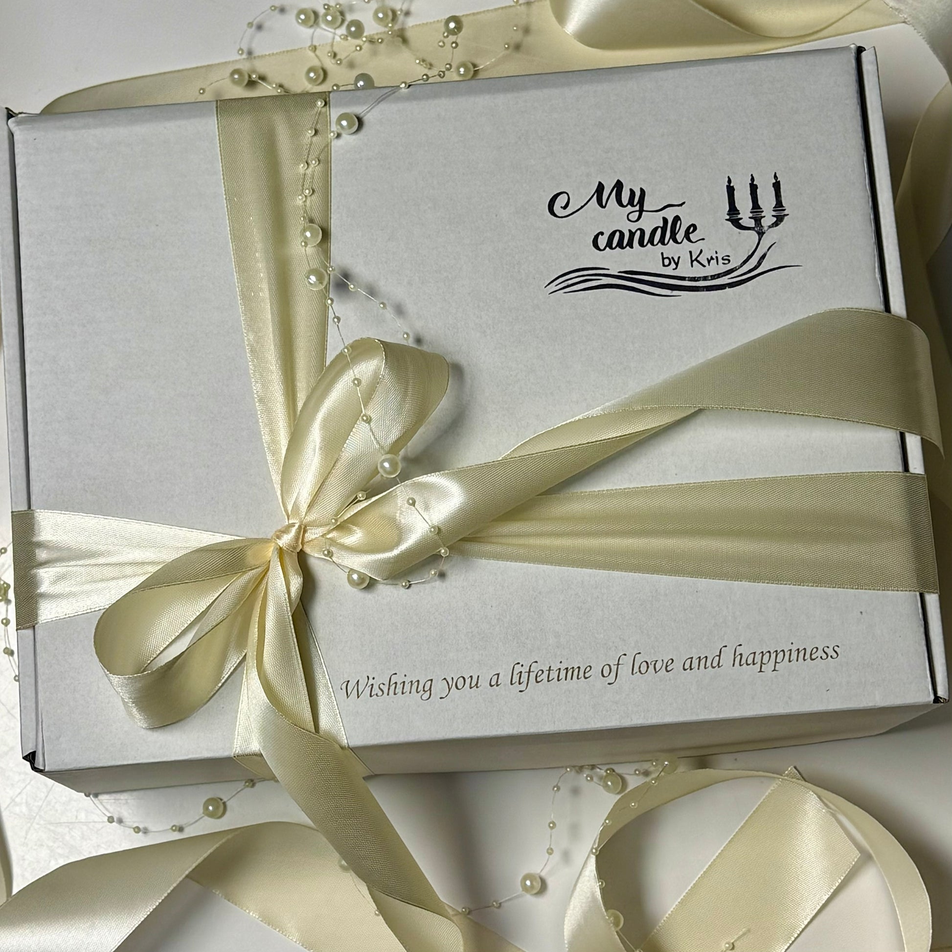 Elegant white presentation gift box from My Candle by Kris, beautifully tied with a ivory satin ribbon, featuring custom laser engraving that reads Wishing you a lifetime of love and happiness.