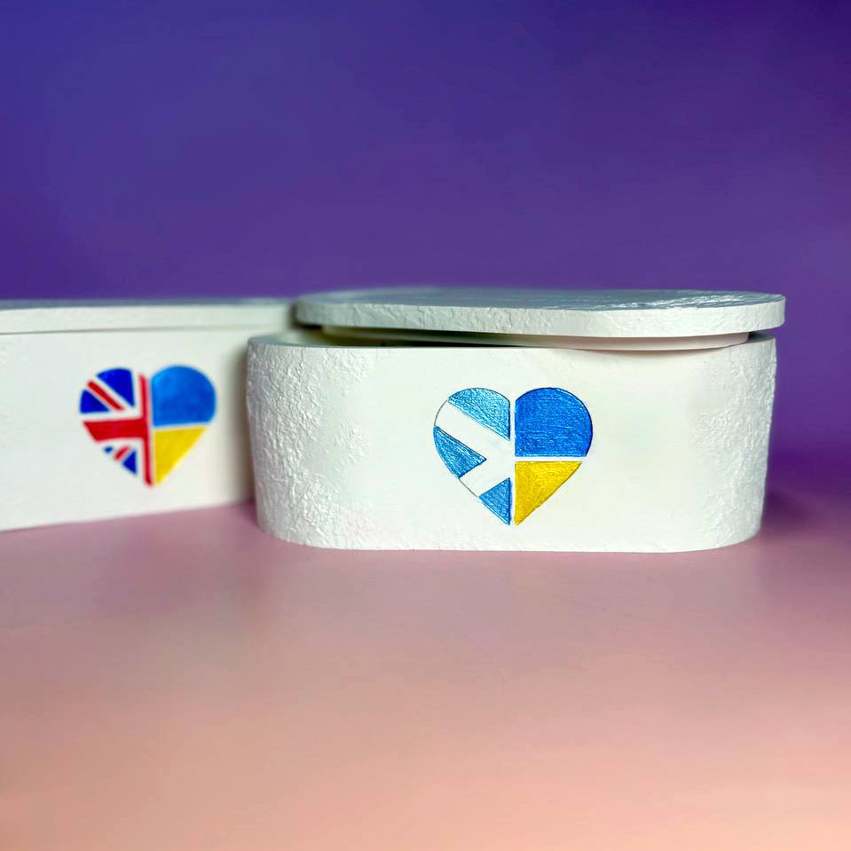 Personalised triple-wick candle in a white Jesmonite pot featuring a hand-painted heart with UK and Ukraine flags as a symbol of gratitude and solidarity.
Bespoke Unity Candles showcasing different flag combinations (Ukraine-Slovakia and UK-Ukraine), celebrating international friendship and support in the UK.
Personalised keepsake candle with a Scotland-Ukraine flag heart, demonstrating the "any two flags" customisation for a unique gratitude gift UK.