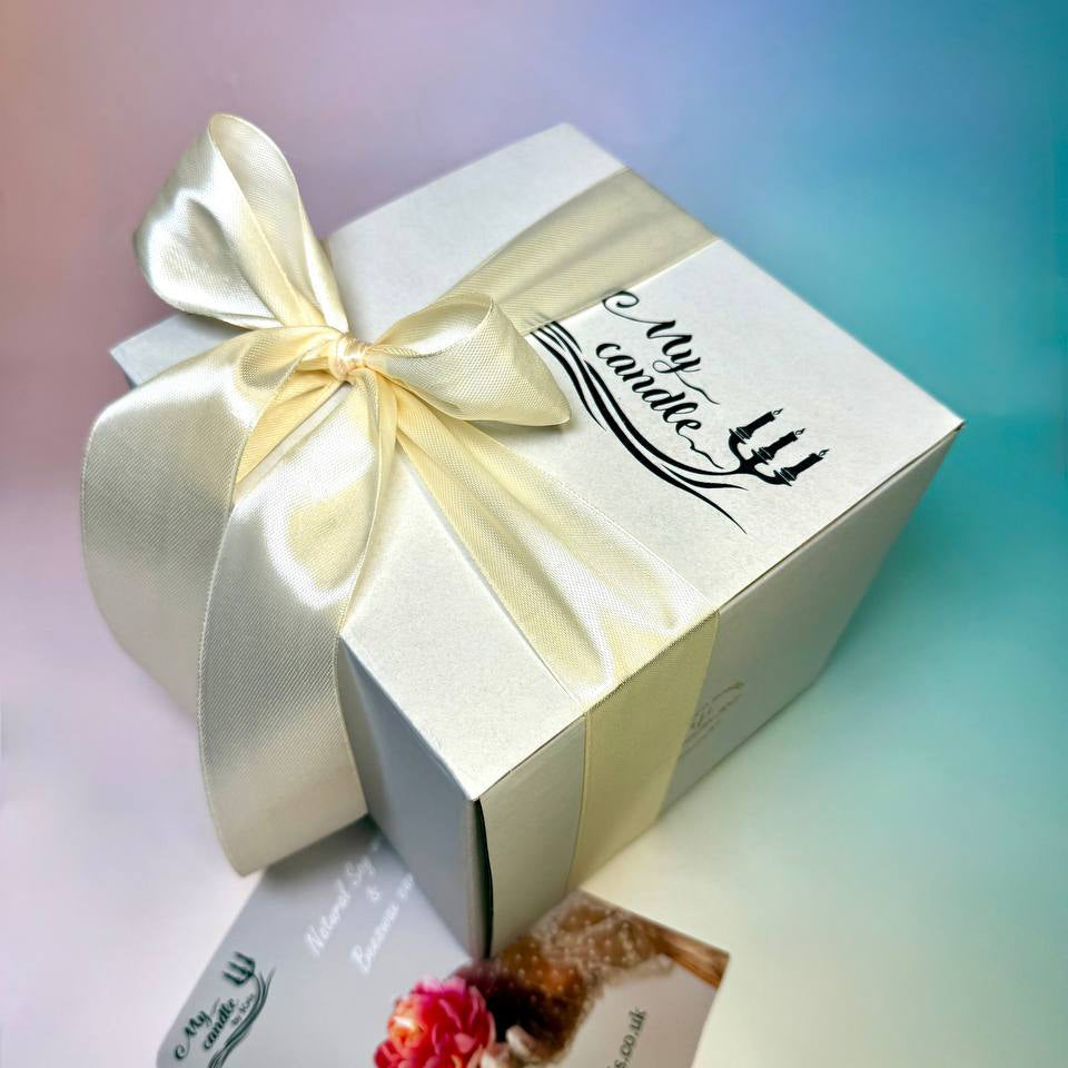 High-angle shot of the "My Candle" gift box finished with a wide ivory satin ribbon and custom engraving.