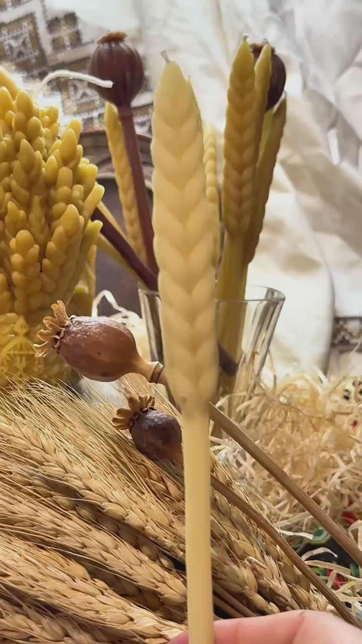 Load video: Video preview cover showing a hand arranging the handcrafted botanical beeswax wheat and poppy candles on a linen fabric background for a spring home fragrance showcase.