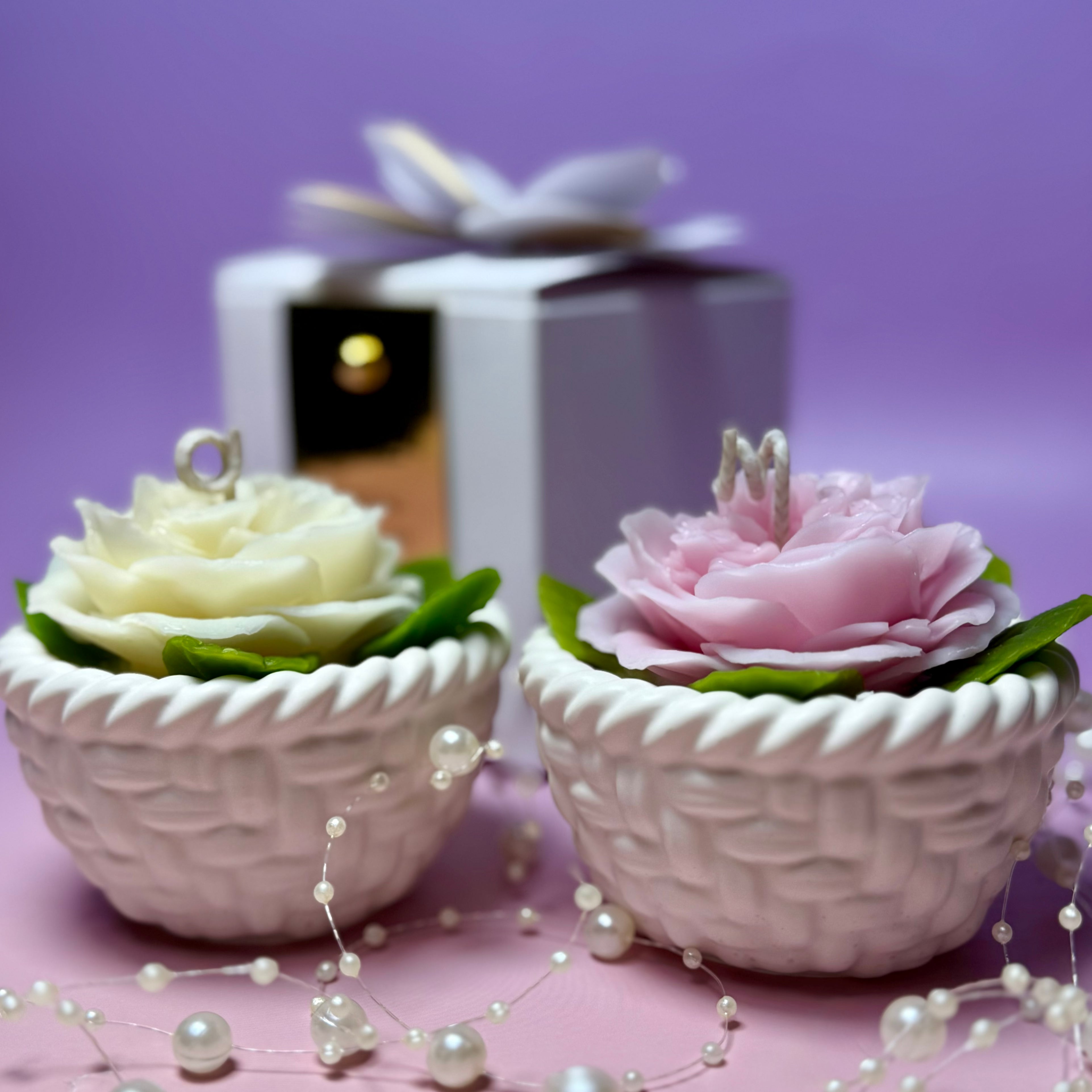 A front-facing presentation of both pink and white Abraham Darby rose basket candles, highlighting the realistic ruffled layers of the beeswax flower heads.