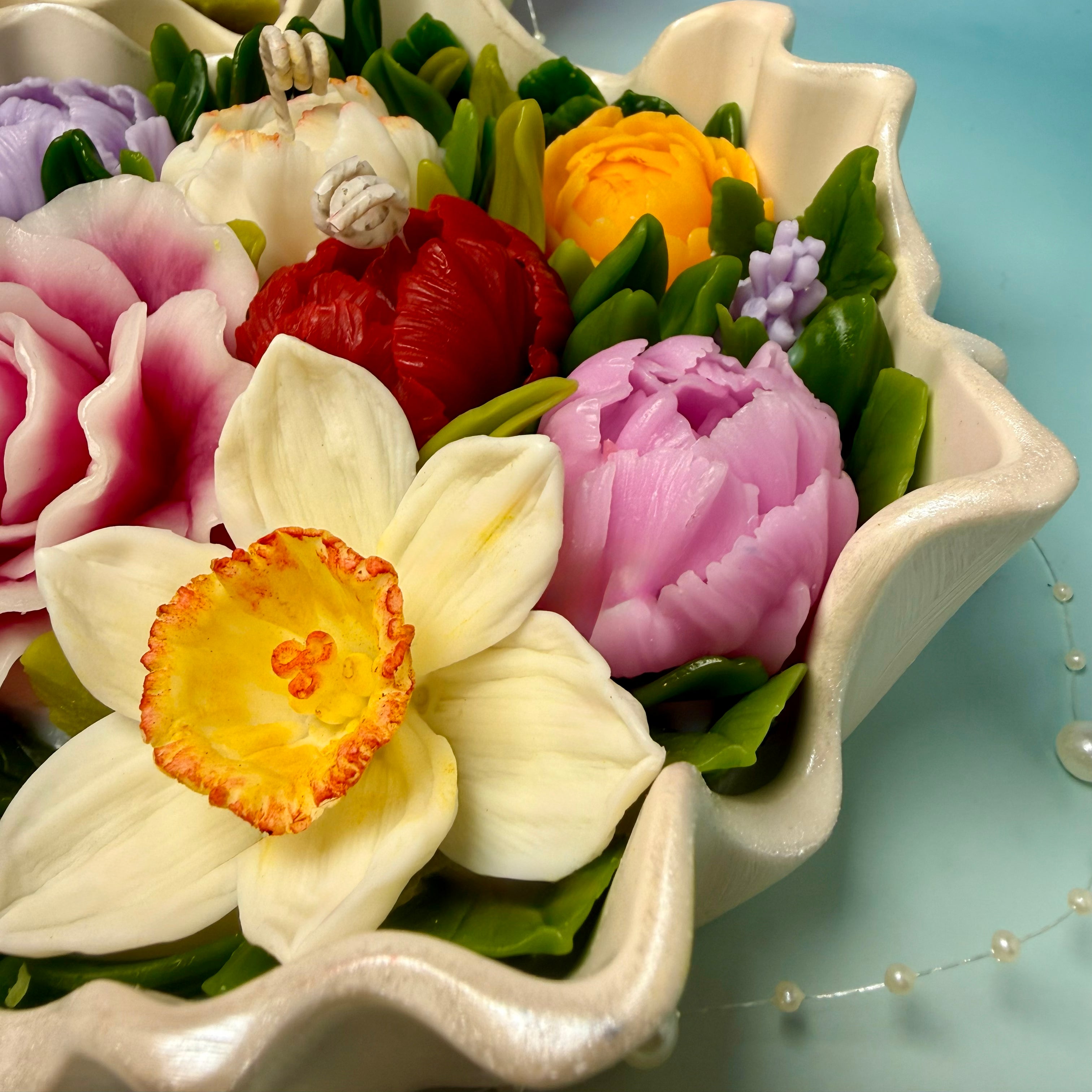 Bird's-eye view of a realistic hand-moulded yellow beeswax narcissus and pink rose bouquet.